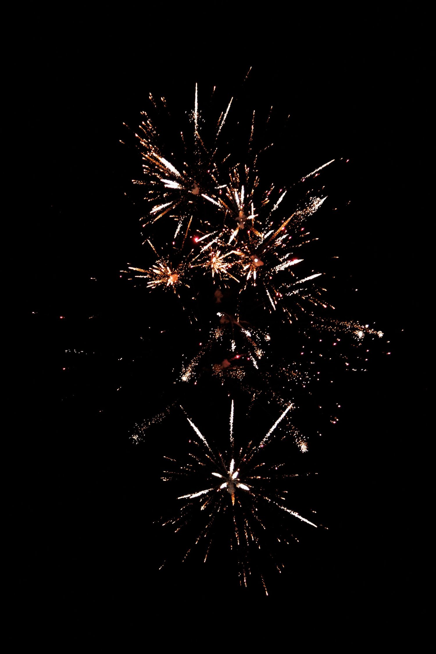 Two golden fireworks bursting against a dark night sky, creating a dazzling display of light and sparks.