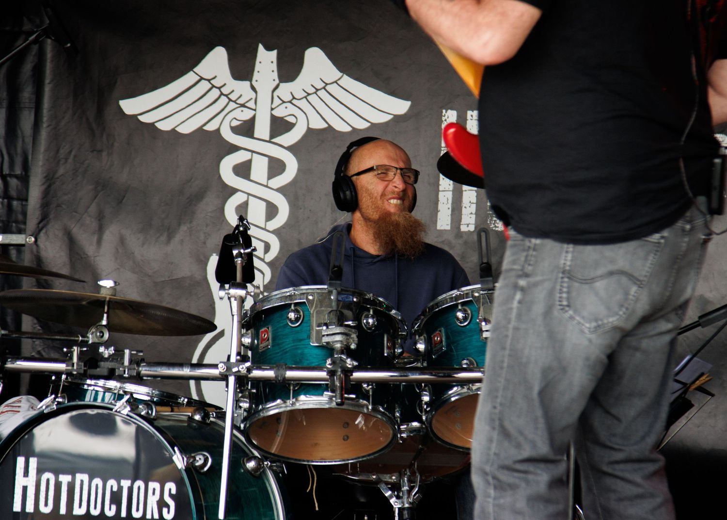 A drum set with the 'Hot Doctors' logo and medical symbol backdrop.