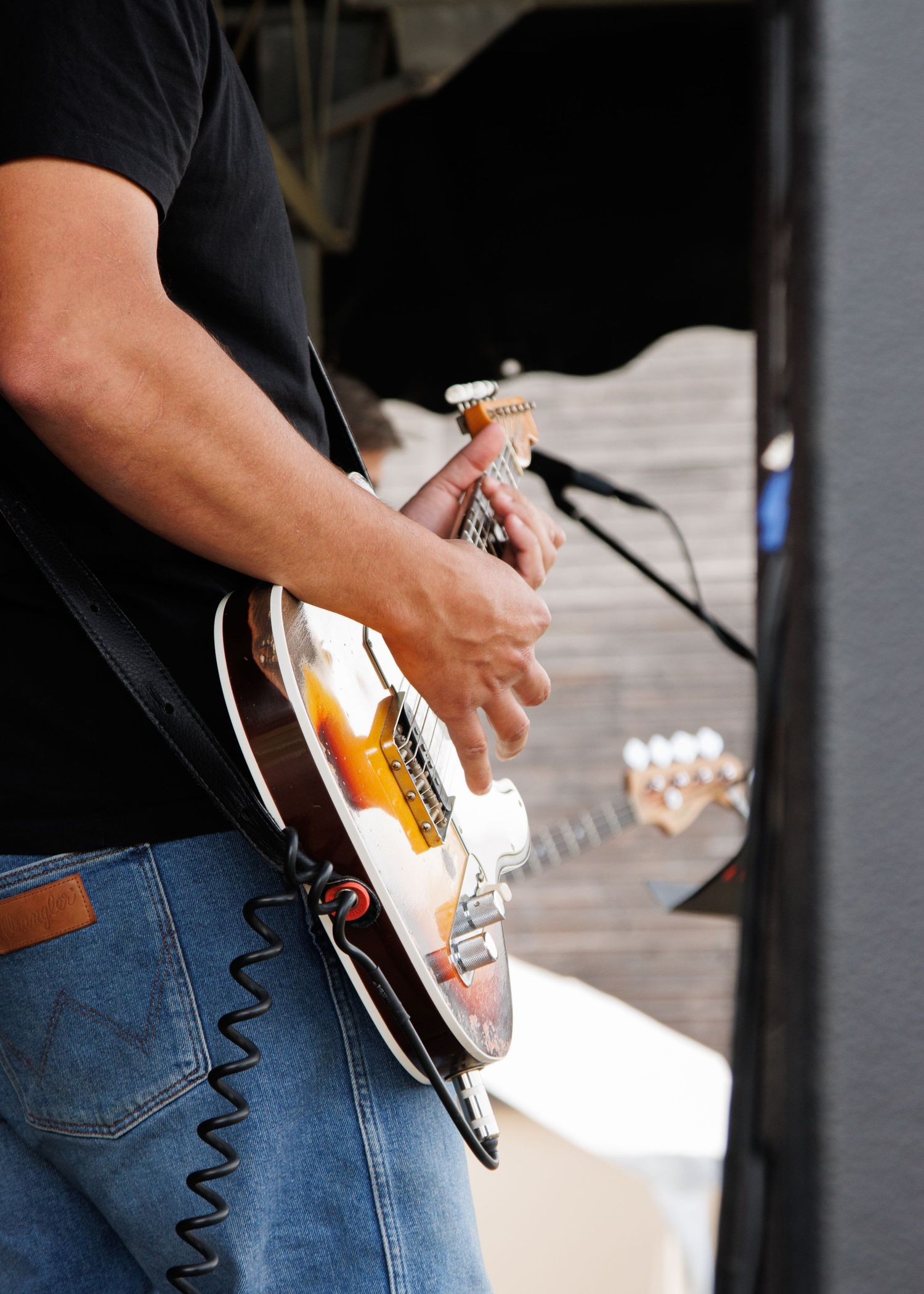 Musician performing with a sunburst electric guitar on stage.
