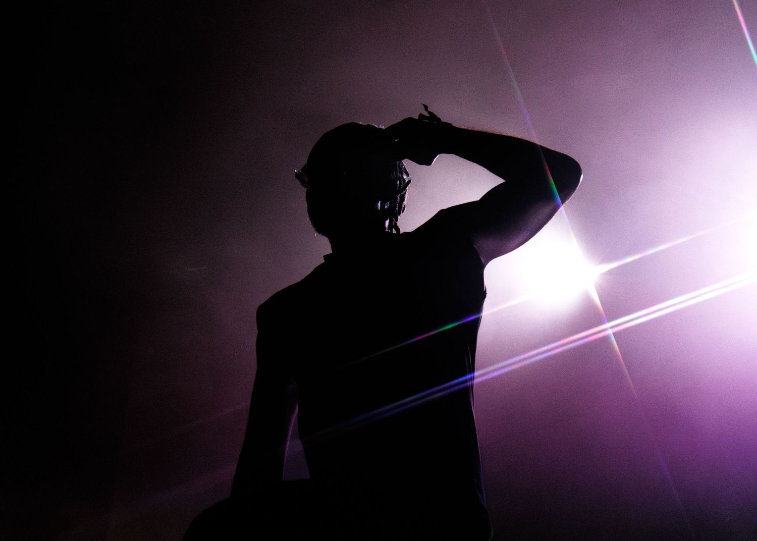 Dark silhouettes of photographers against a purple sky with bright lens flares and starbursts.