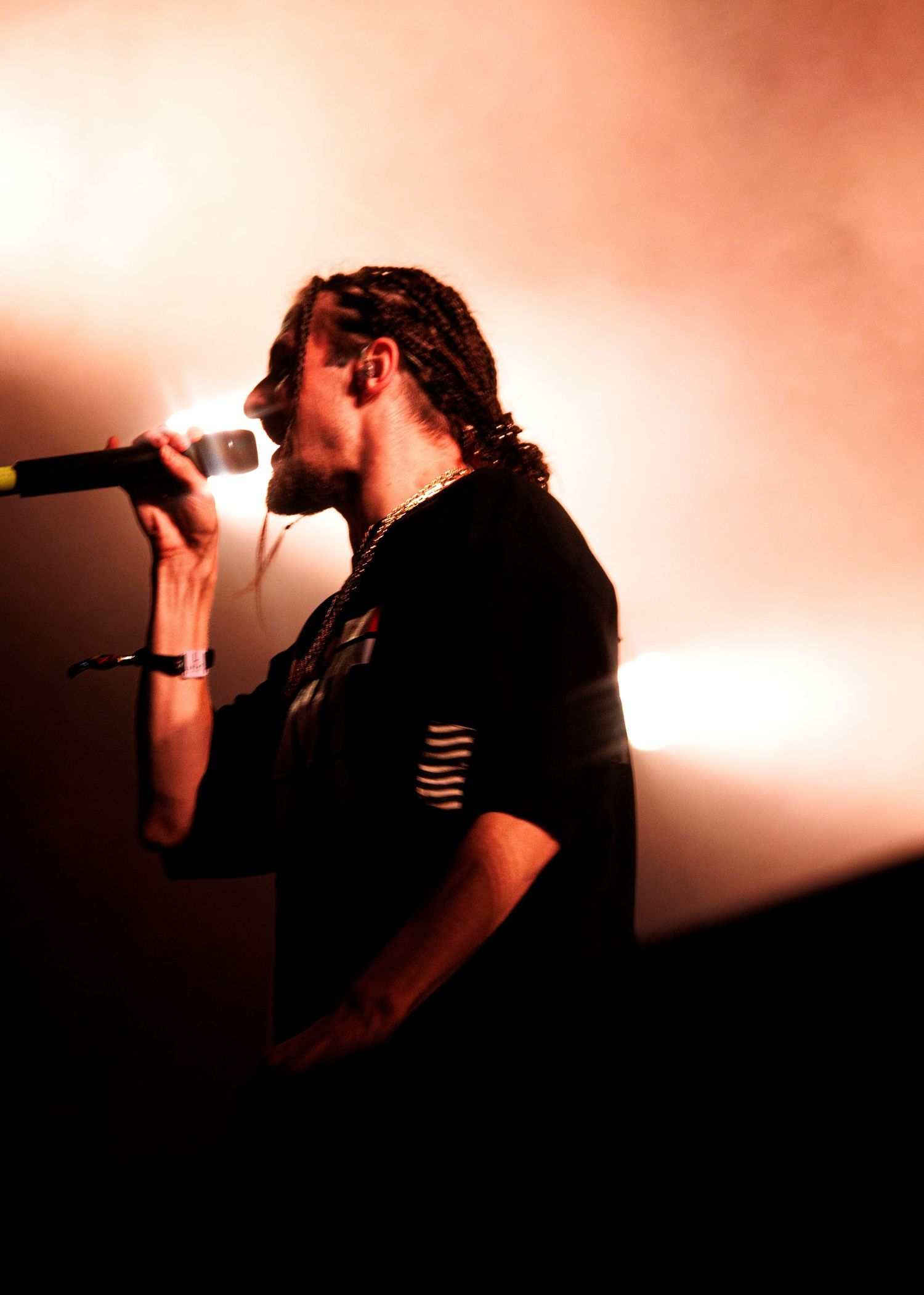 Silhouetted figure performs on stage in dramatic lighting with microphone creating atmospheric performance shots.
