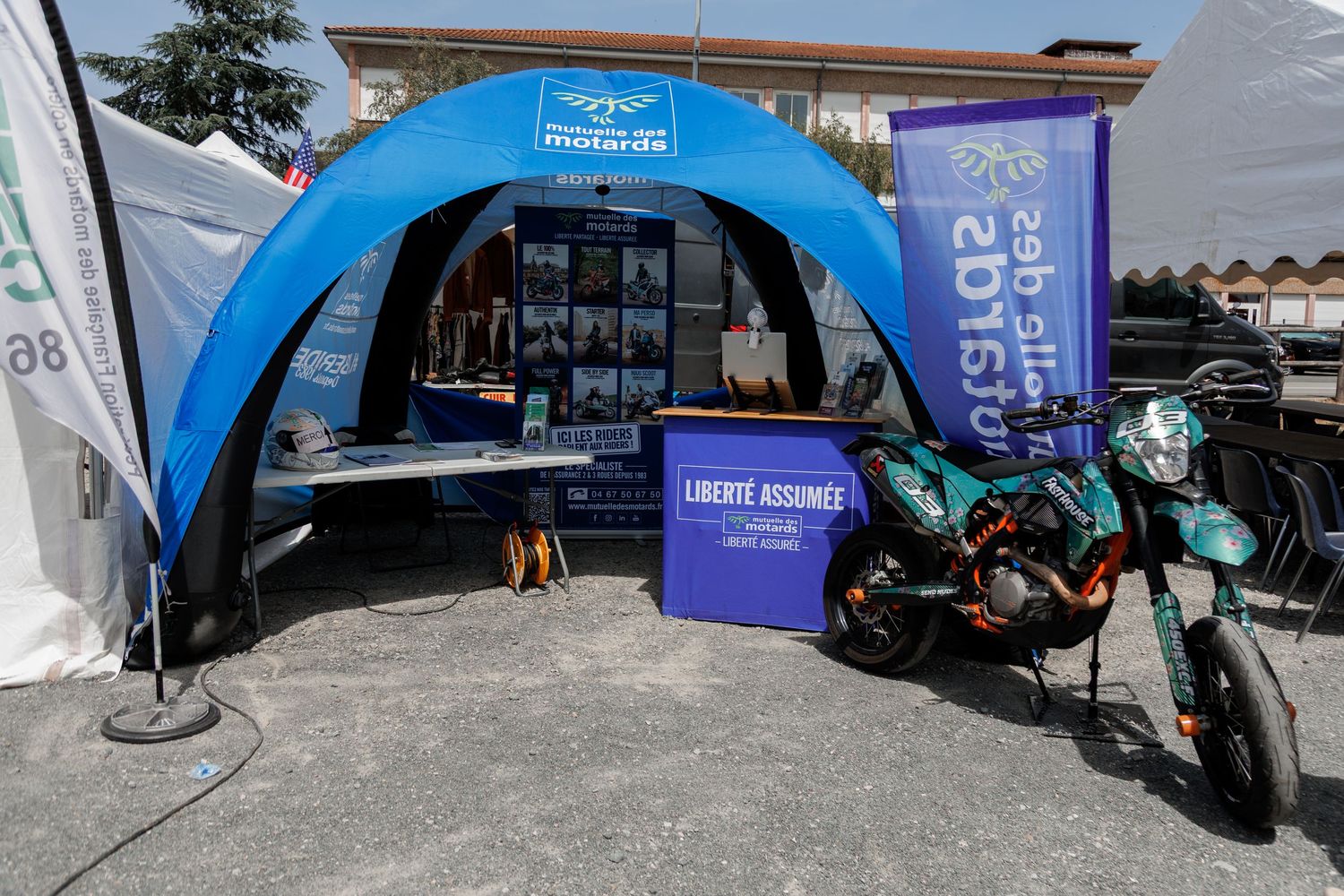Blue inflatable tent at a motorcycle expo with a green dirt bike displayed outside on a sunny day.