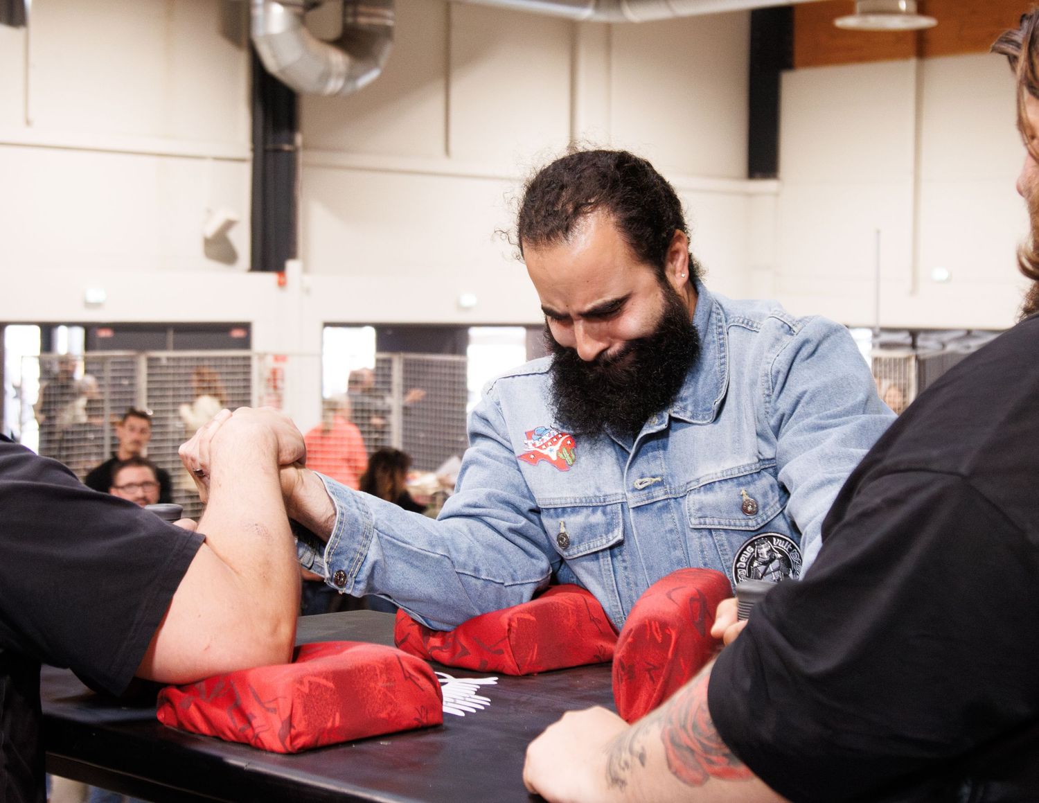 Two people practicing arm wrestling techniques on a red pad during training.