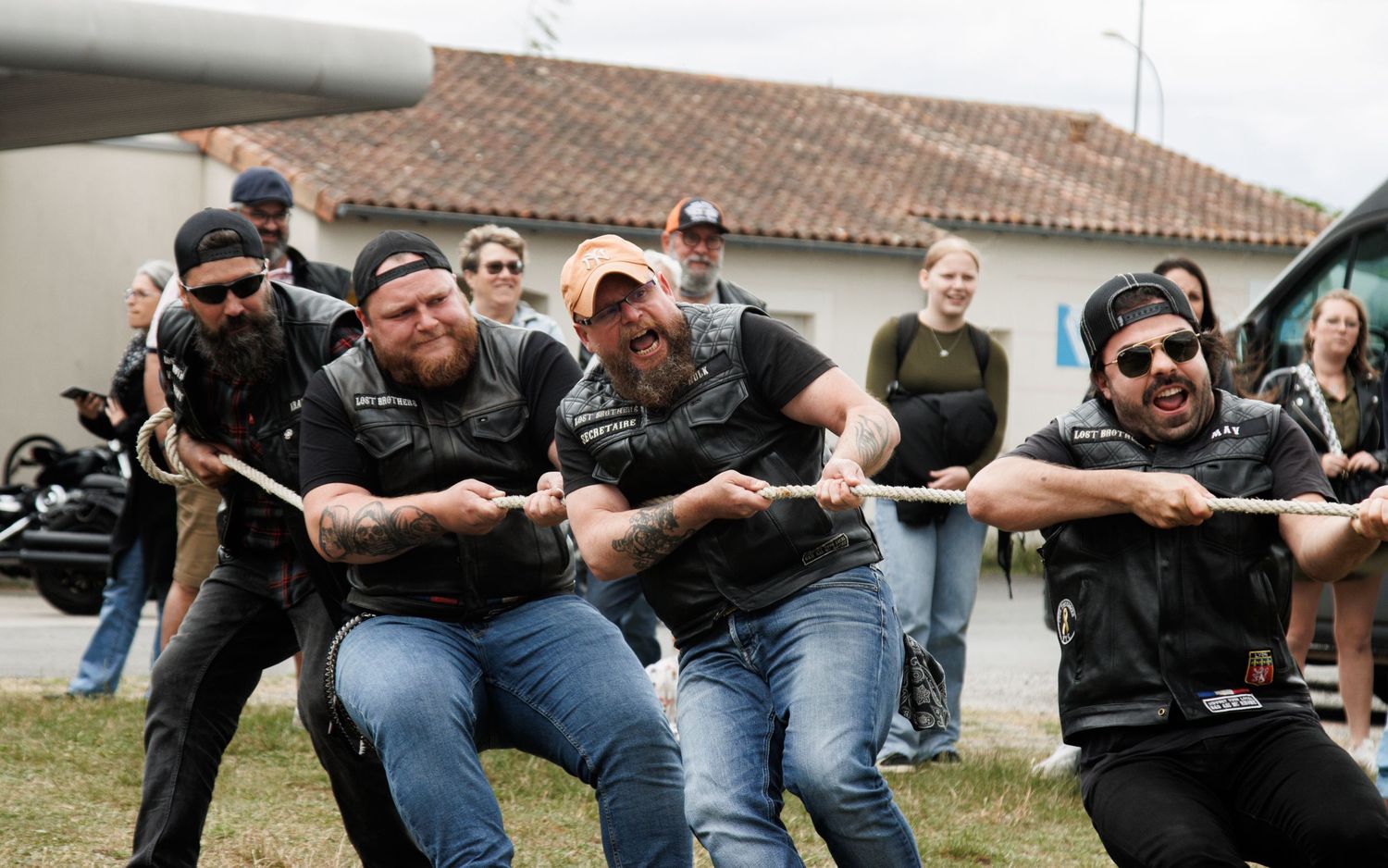 Row of people in black leather sitting and posing together outdoors.
