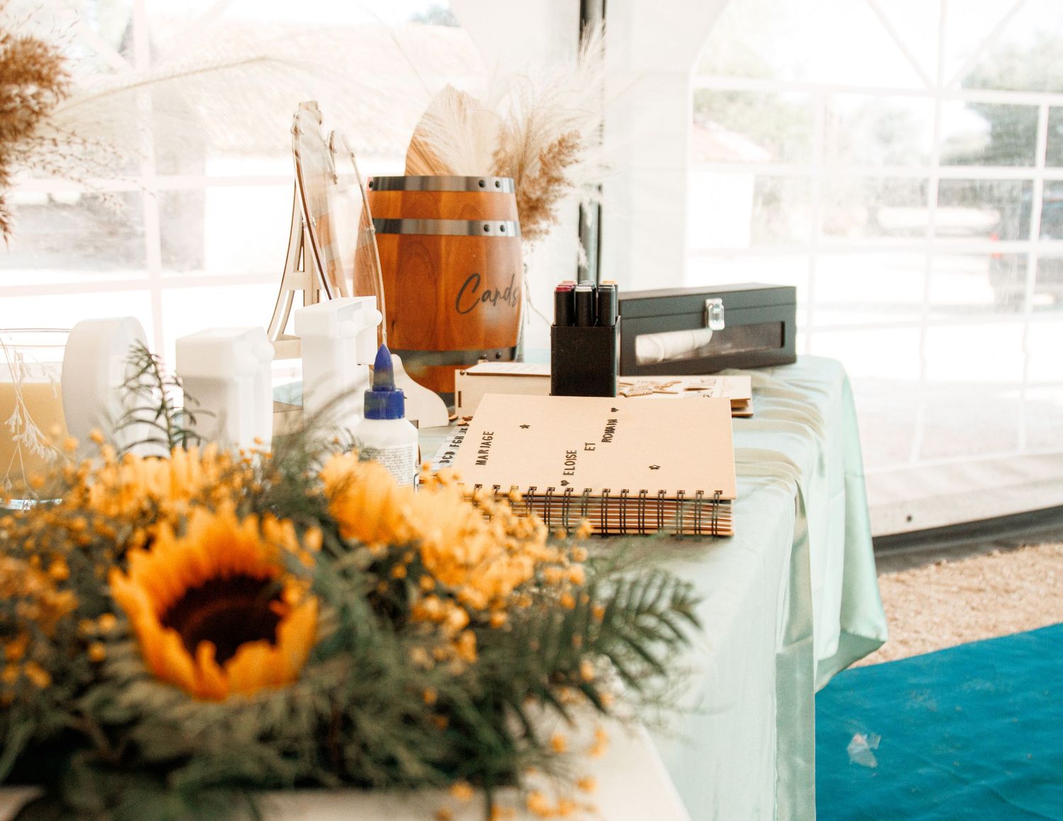 Wedding reception table settings feature bright sunflowers and eucalyptus with a blue pool in the backdrop.