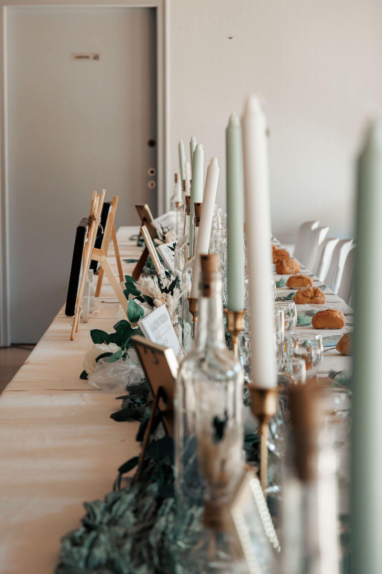 Elegant wedding reception table with tall candles, greenery runner, and place settings.