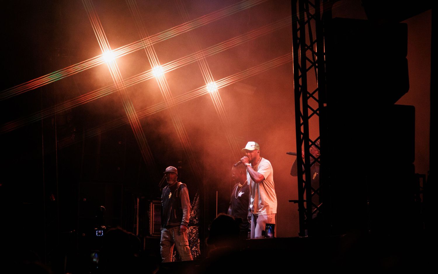 Concert performer silhouetted on dark stage with dramatic orange lighting and fog effects during live music performance.