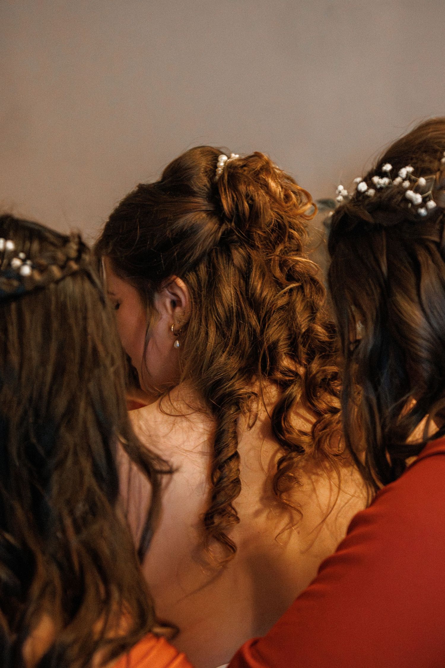 Women with elegant updo hairstyles adorned with pearl hair accessories, viewed from behind at a formal event.