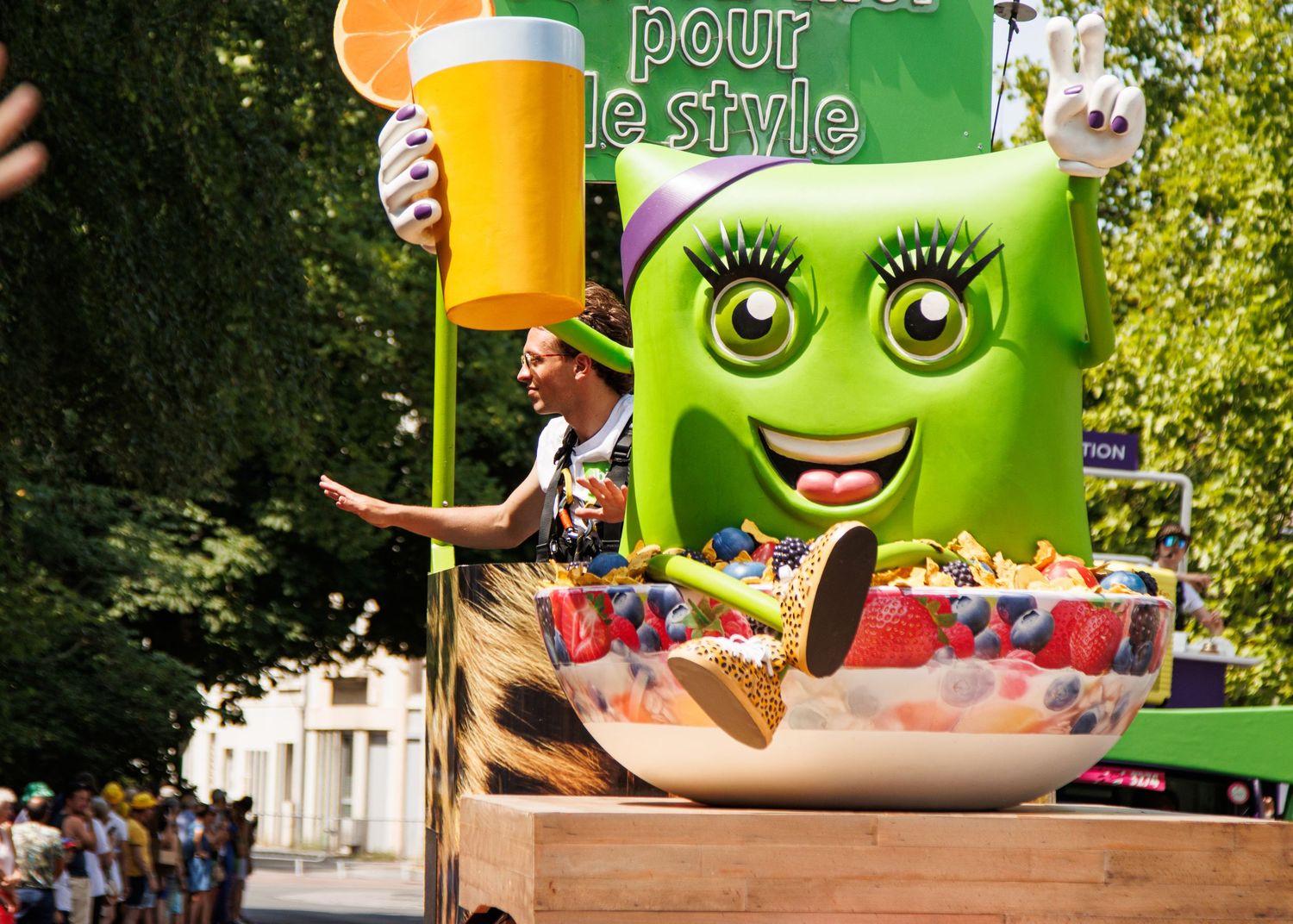 A festive float featuring a green cartoon character holding a large beer mug and food items.