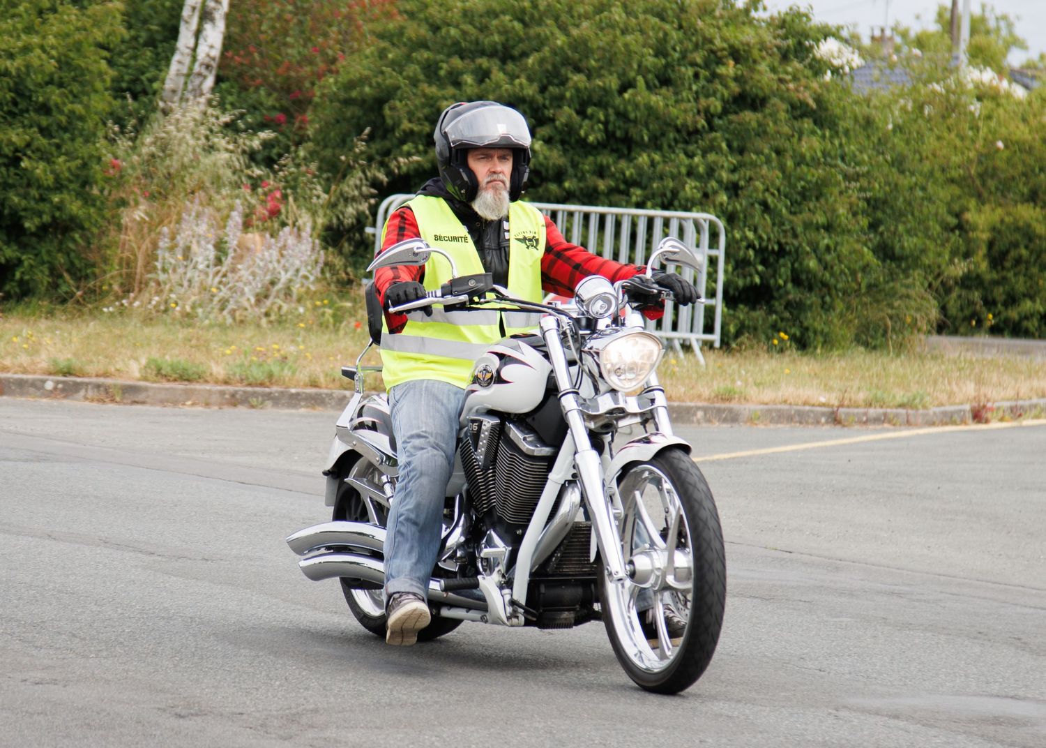 A custom white motorcycle being ridden on an asphalt road.