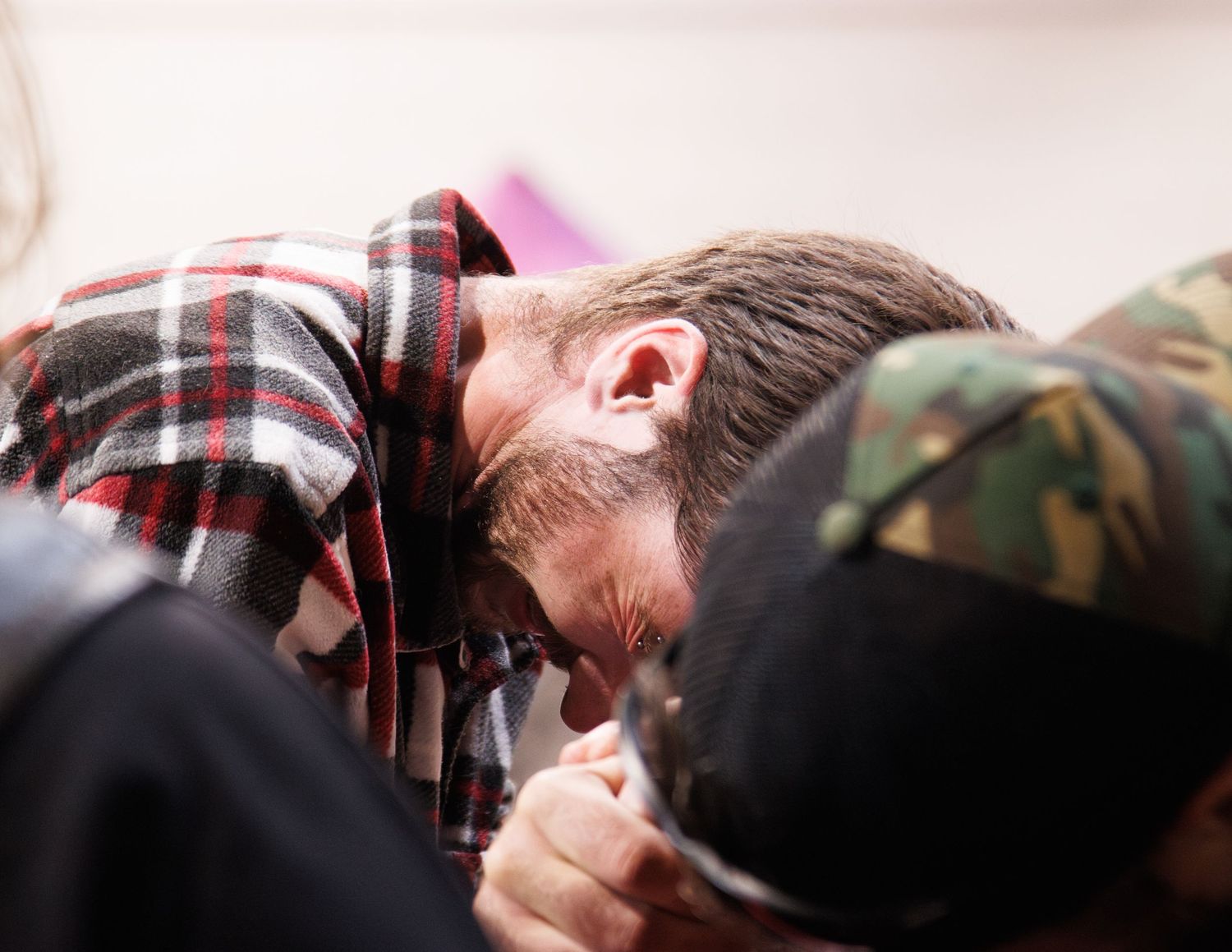 People gathered around table watching intense arm wrestling match.