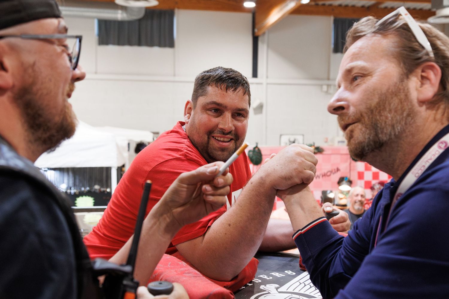 Three men laughing and pointing at a table during a casual indoor social gathering or gaming event.