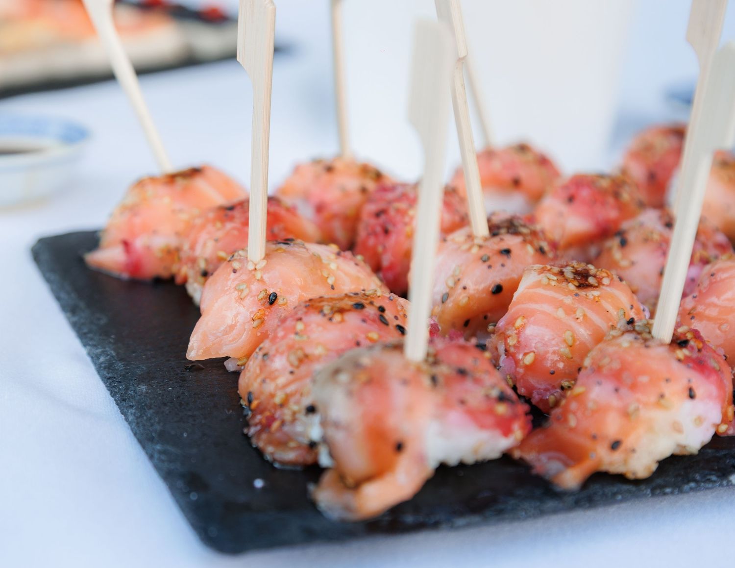 Delicate salmon and shrimp appetizer bites on skewers displayed on dark slate serving board.
