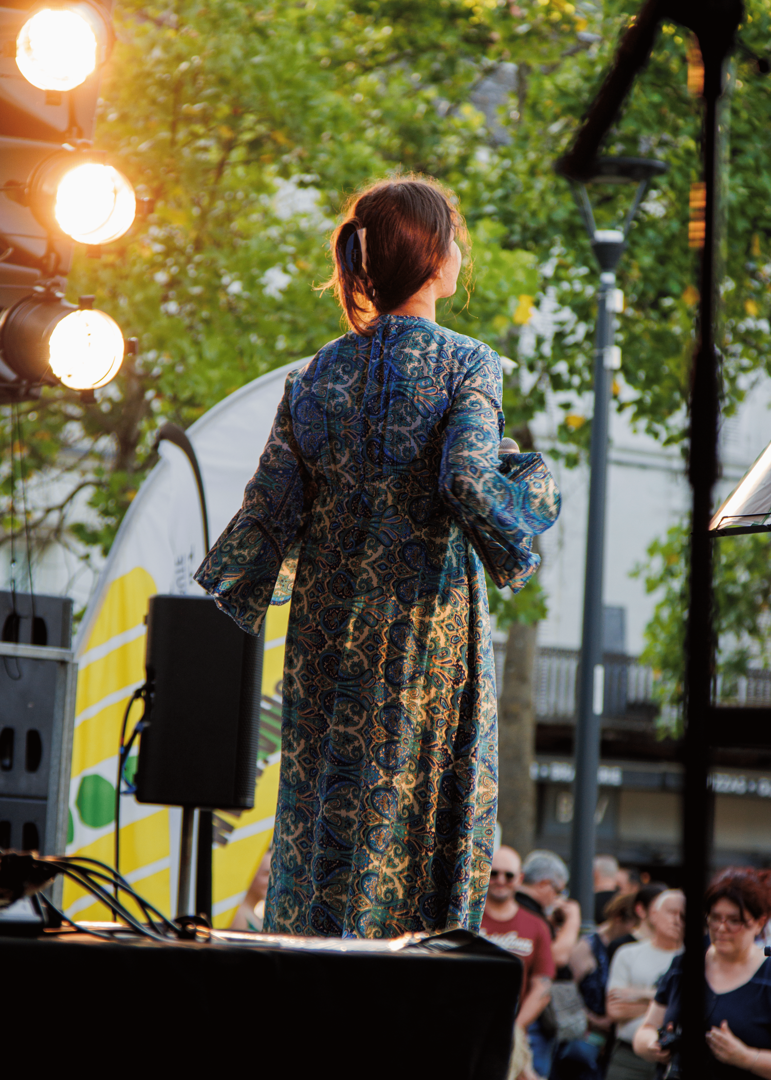 Evening outdoor performance setup with stage lights illuminating trees in the background.