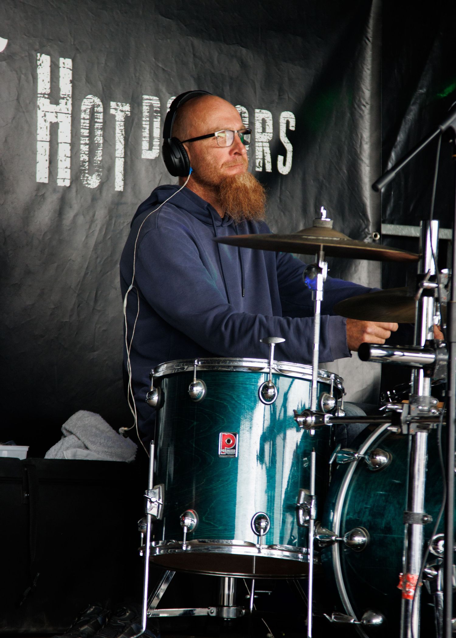 Drummer performing on a green drum kit against a dark backdrop during a live music performance.