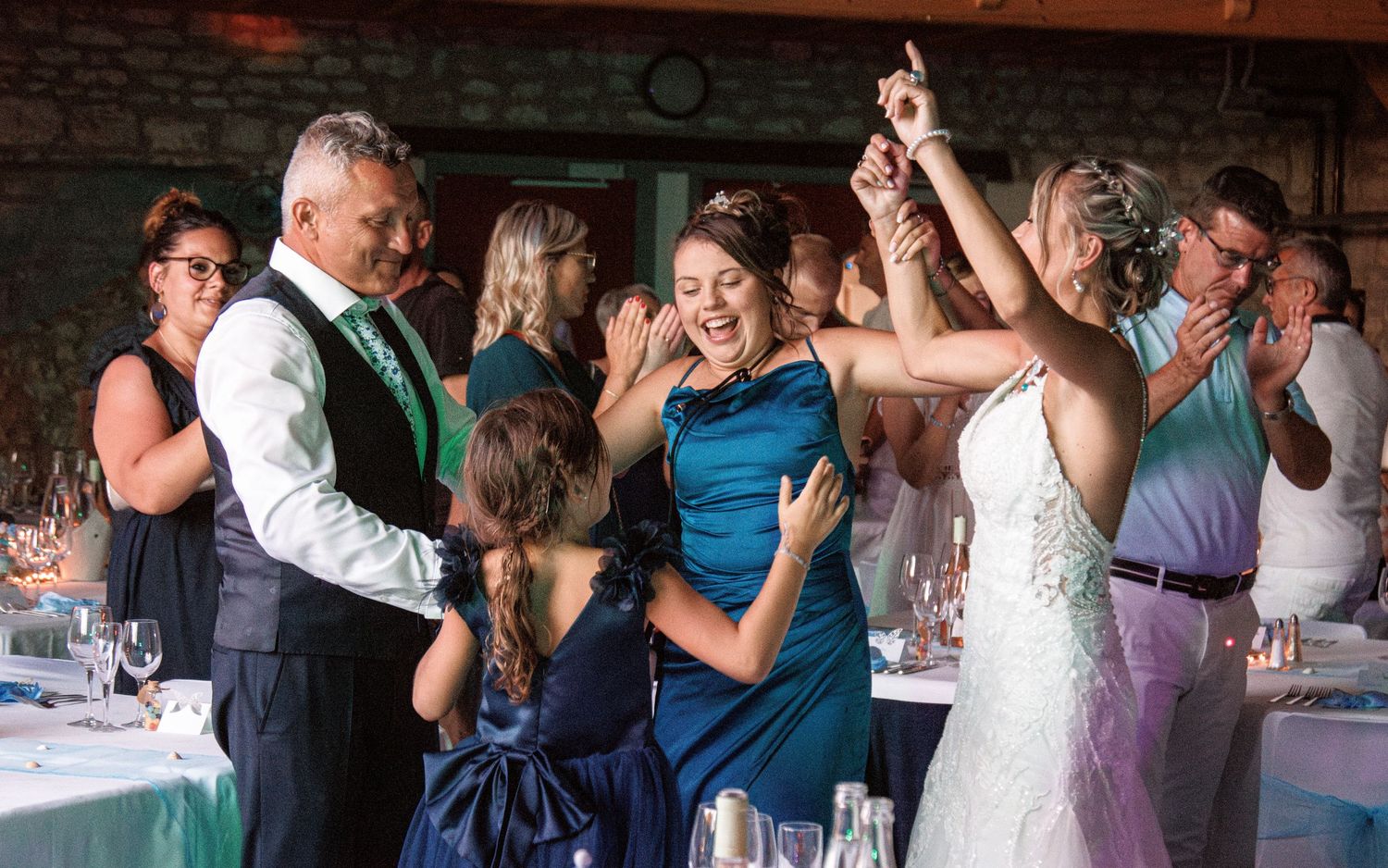 Wedding reception guests dancing and celebrating together in a rustic indoor venue.