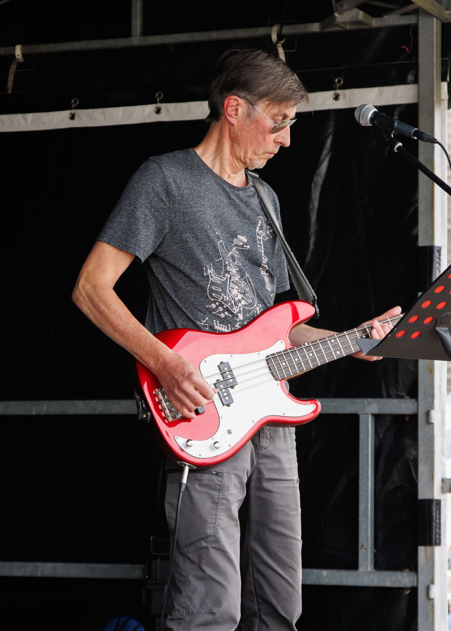 Bass player performing with red electric bass guitar on stage.