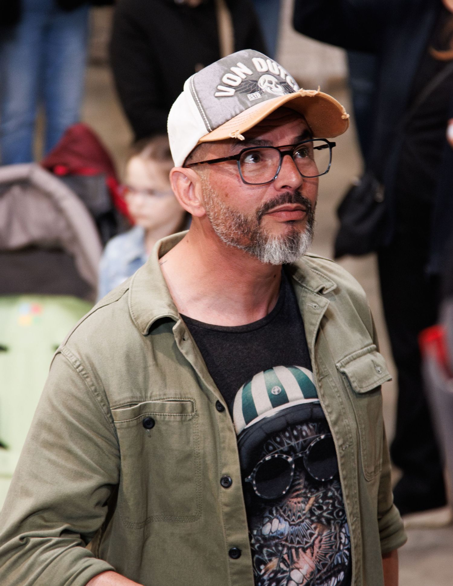 A crowd gathers at an outdoor event wearing casual clothing and baseball caps.
