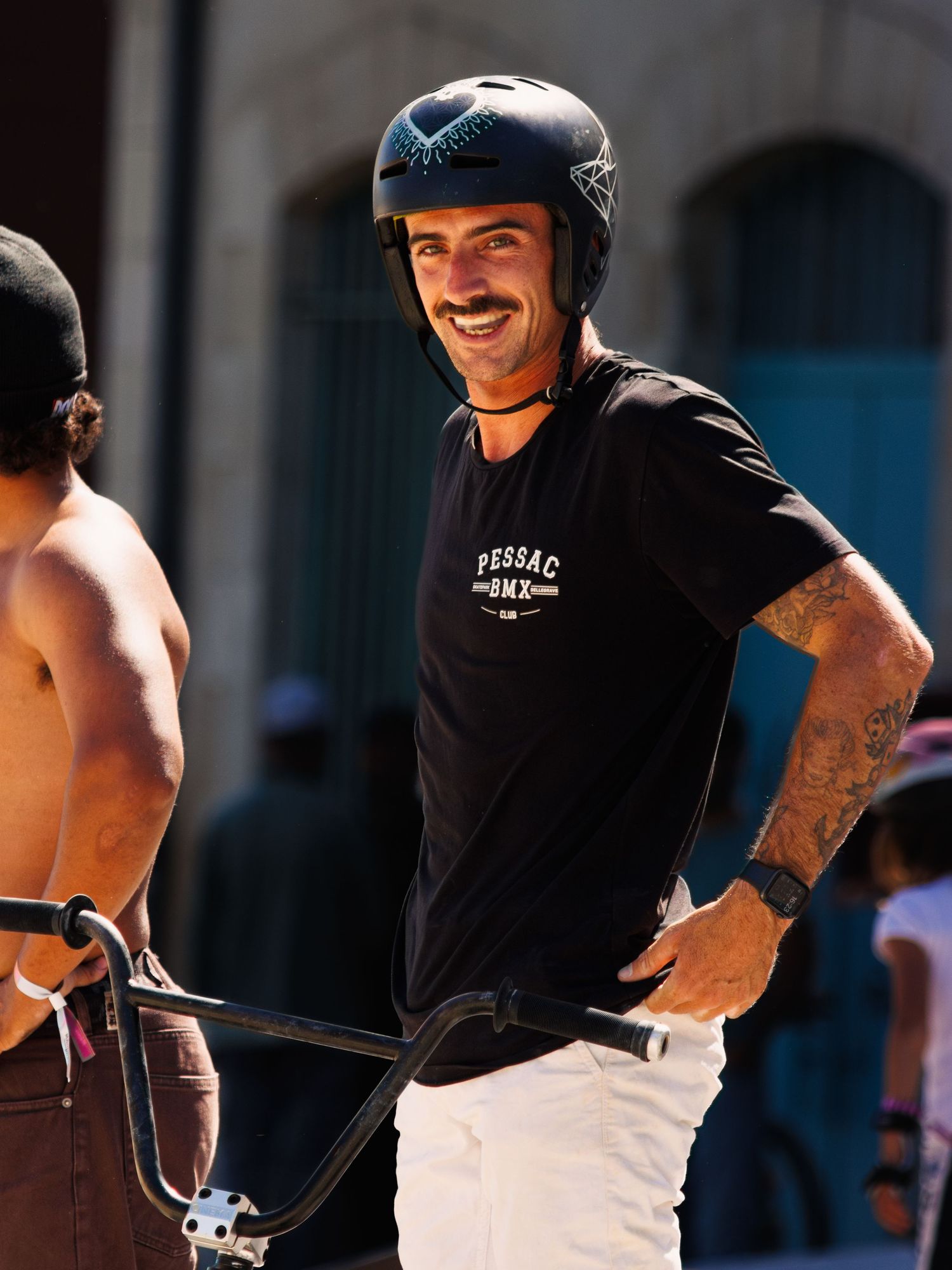 Person wearing black t-shirt riding bicycle in bright sunlight.