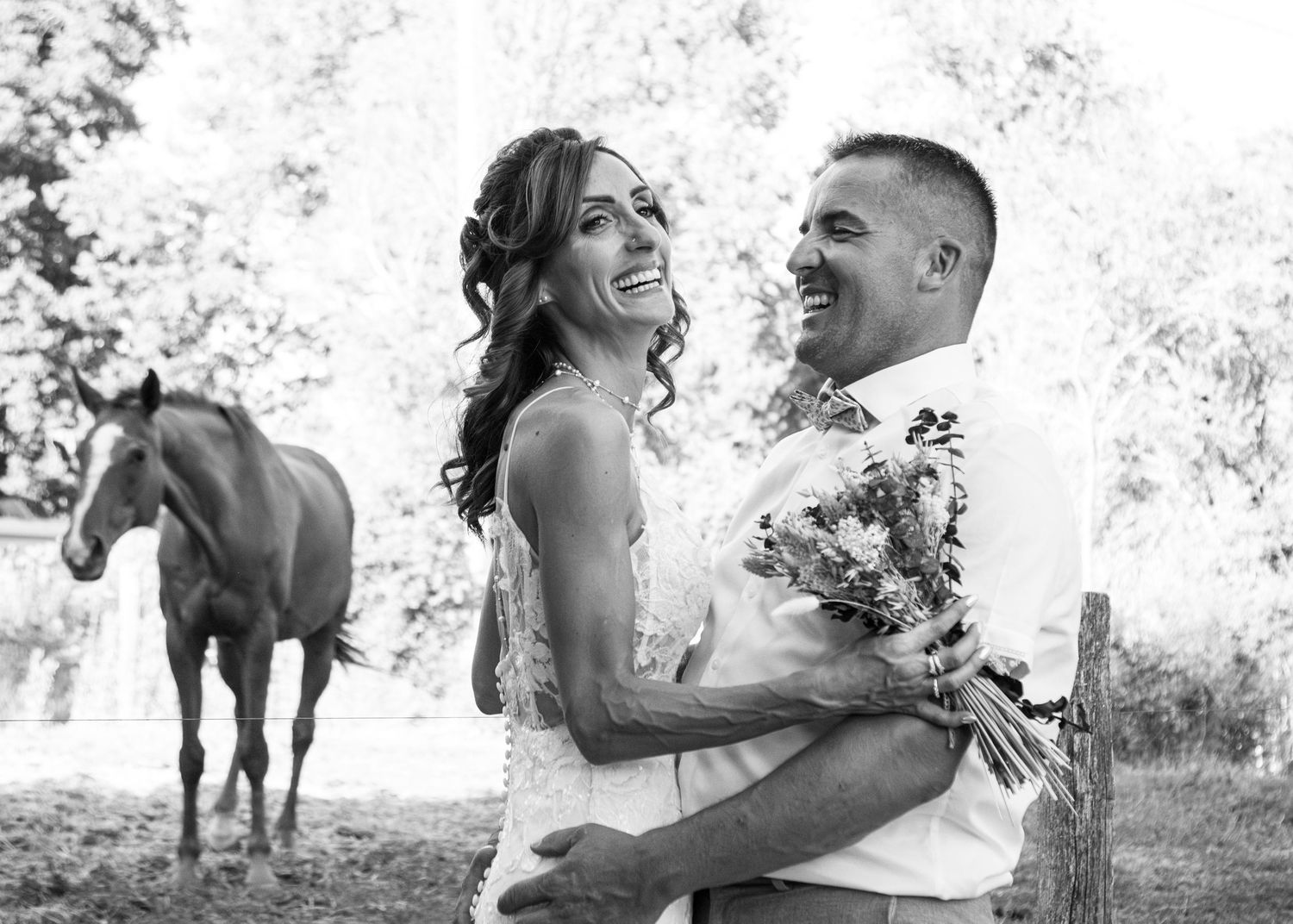 A romantic black and white engagement photo session featuring a couple and their horse in a dreamy outdoor setting.