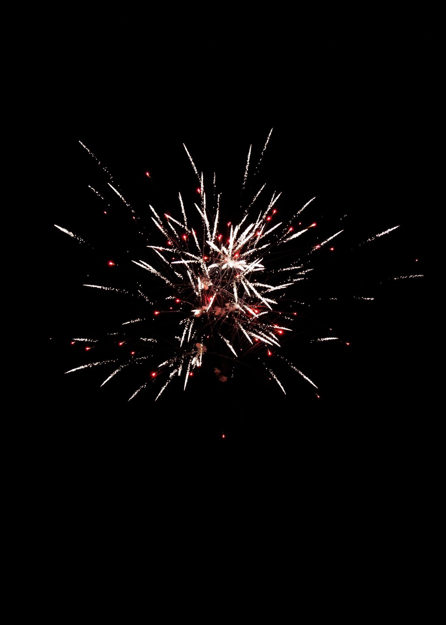 Red and white fireworks burst against a dark night sky in a dazzling star-shaped explosion display.
