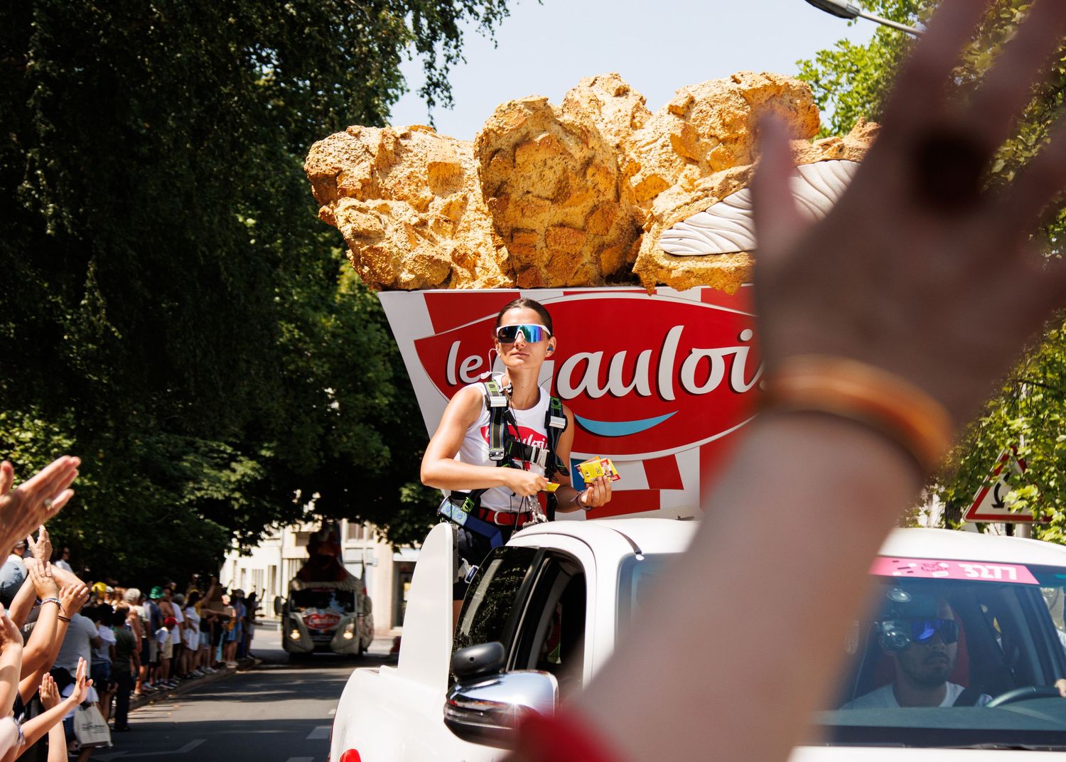 Promotional parade float with Gauloises branding drives through a crowd-lined street on a sunny day.
