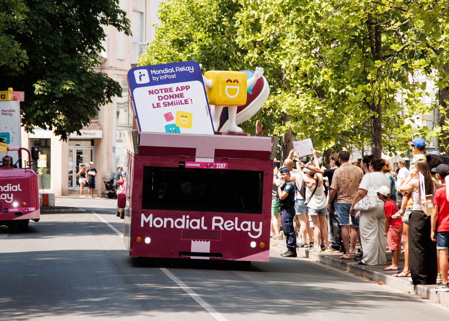 A Mondial Relay branded promotional vehicle participates in a street parade with spectators.