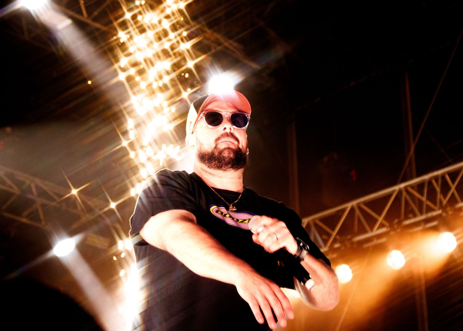 Concert performer silhouetted against bright stage lights during an energetic musical performance.