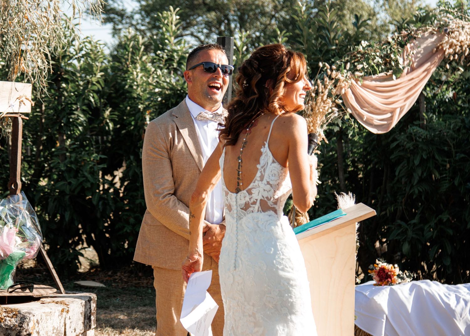 A couple shares their first dance at an outdoor wedding reception surrounded by trees and natural light.