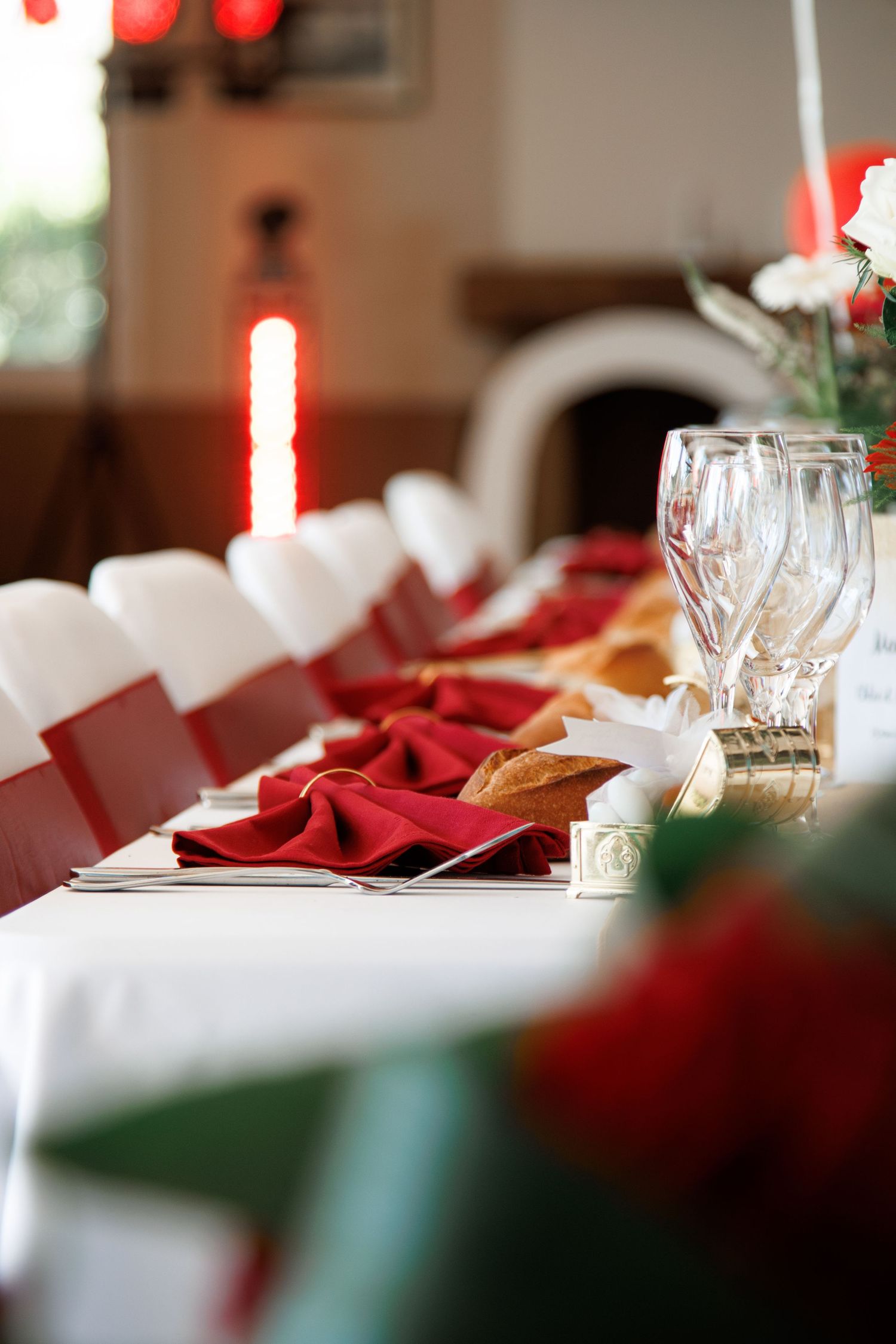 Elegant wedding reception table set with red napkins, crystal glasses, and floral centerpieces.