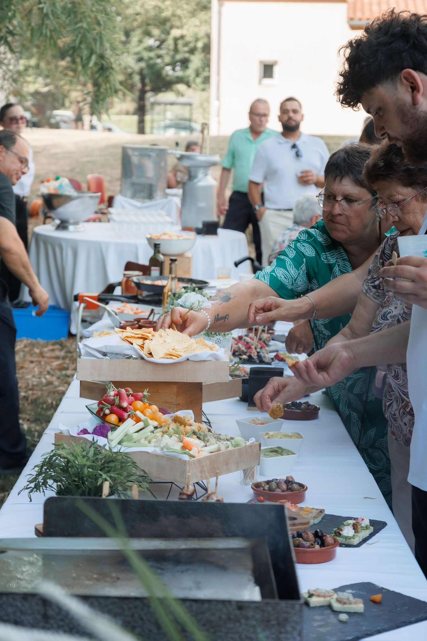 Wedding guests selecting food from an elaborate outdoor buffet table with fresh appetizers.