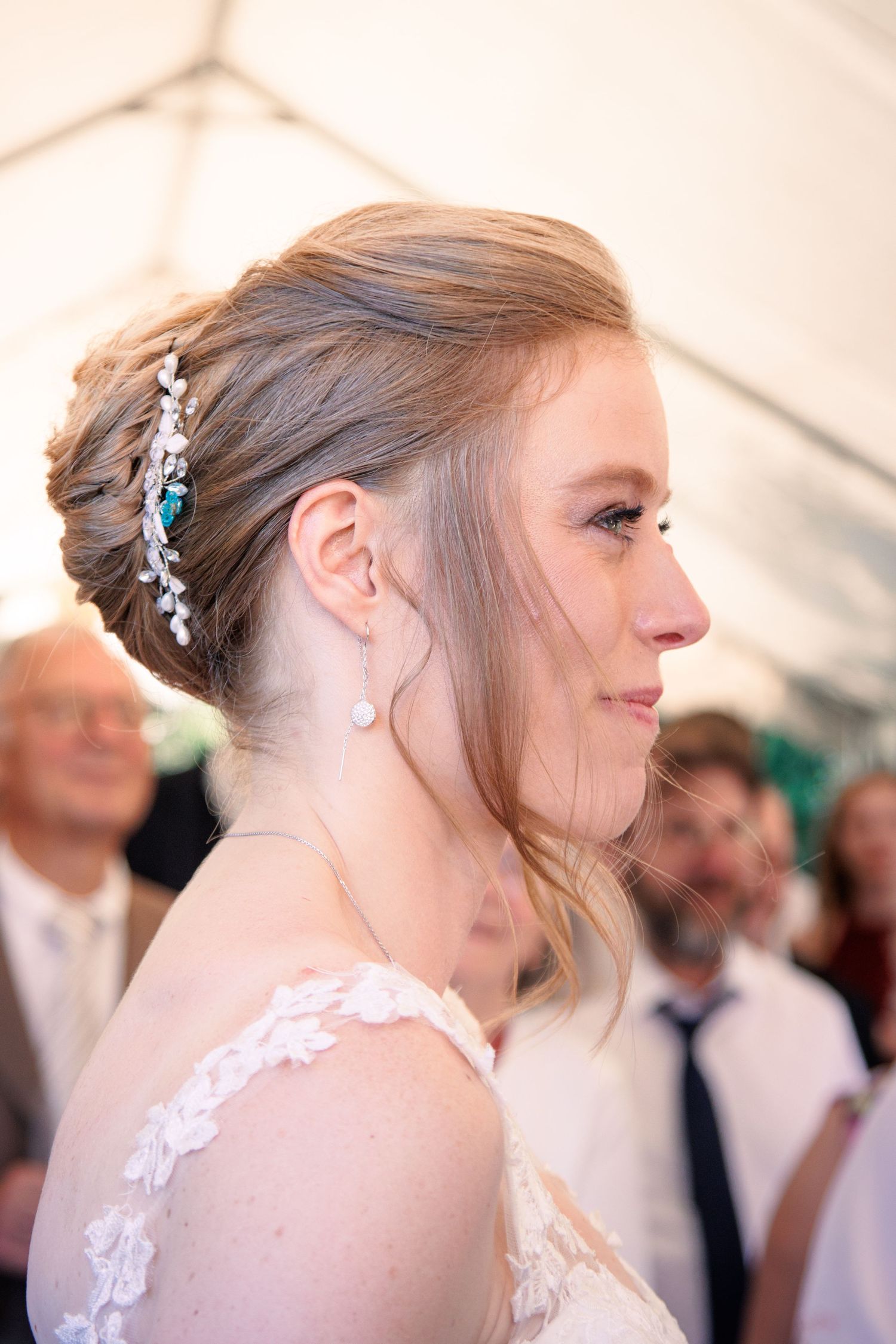 Close-up profile of a bride with an elegant updo adorned with a jeweled hair accessory and pearl earring.