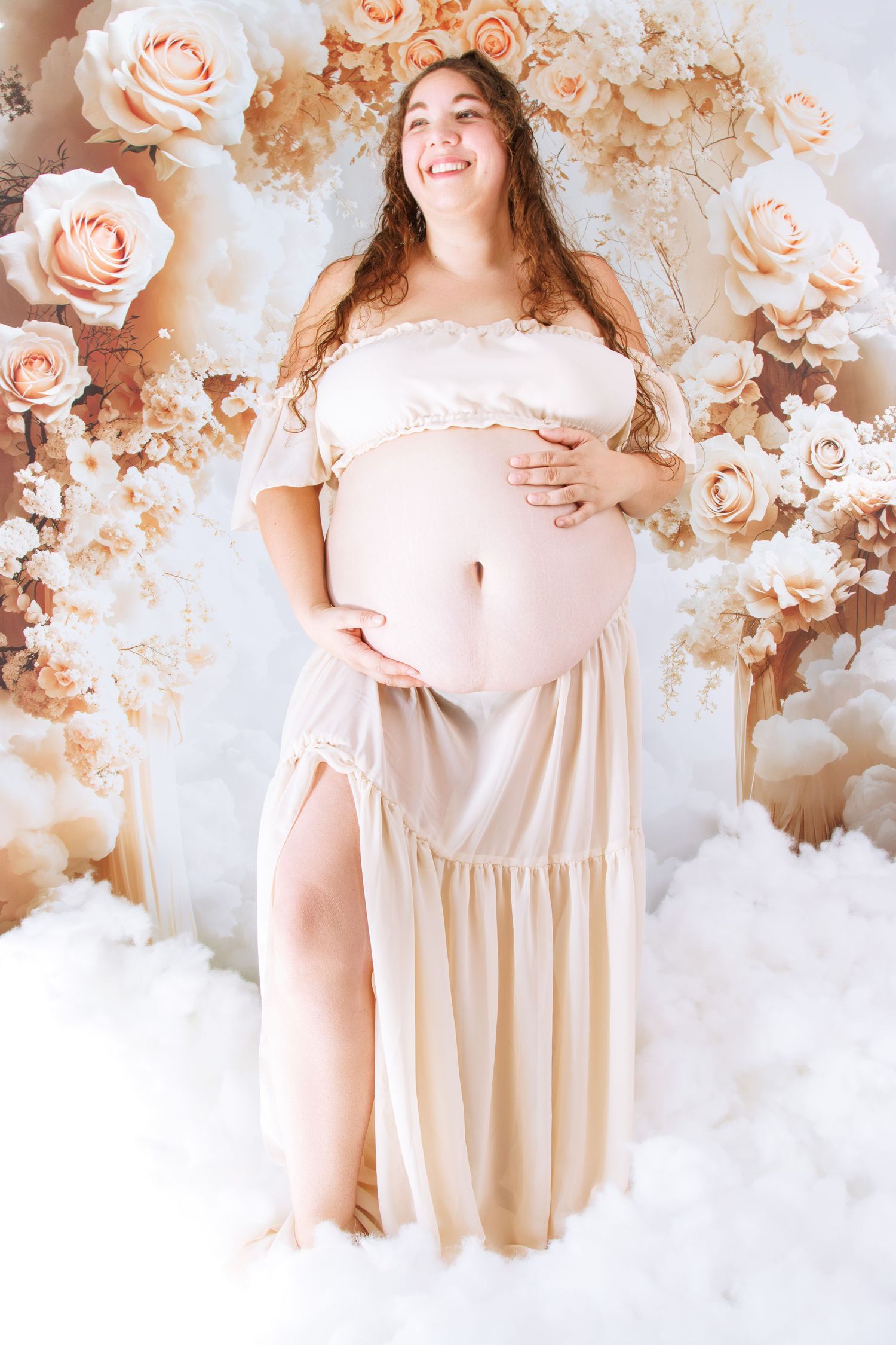 Maternity photo shoot featuring delicate peach roses and soft white clouds in dreamy lighting.