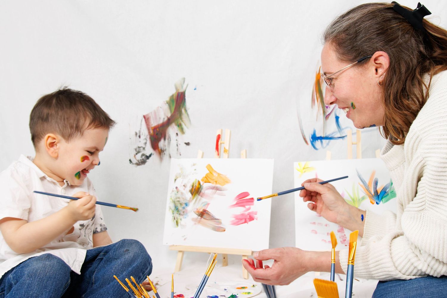 Art session showing joyful painting activity with brushes and bright colors.