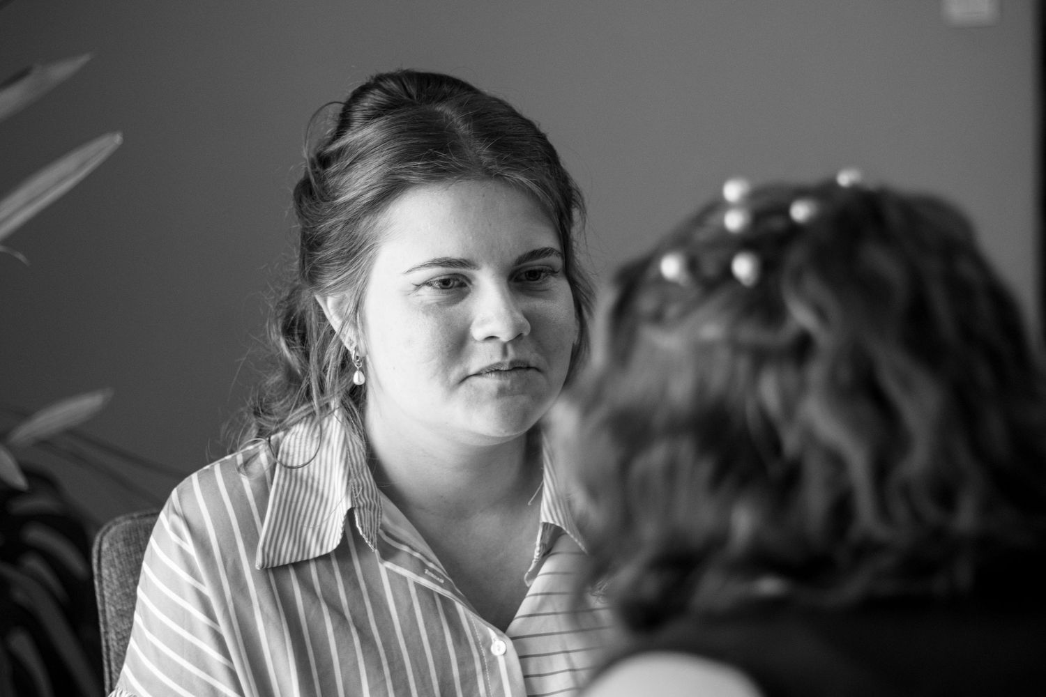 Black and white portrait of a young woman with updo hairstyle listening attentively during a conversation.