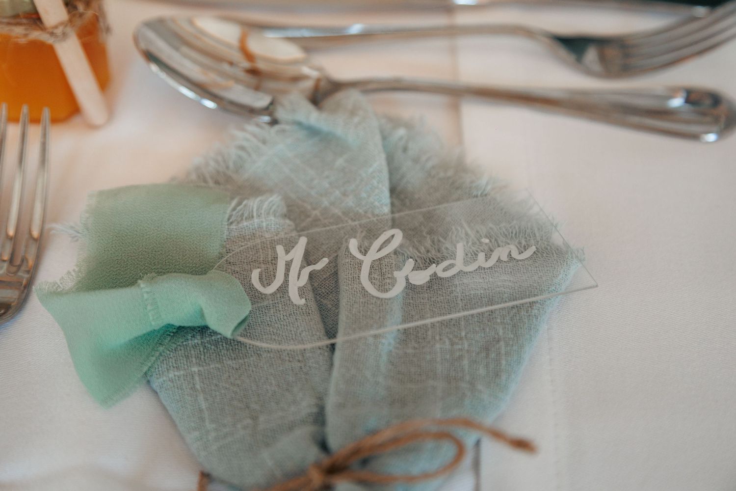 Elegant wedding place setting with mint green linen napkin and personalized wooden name tag.