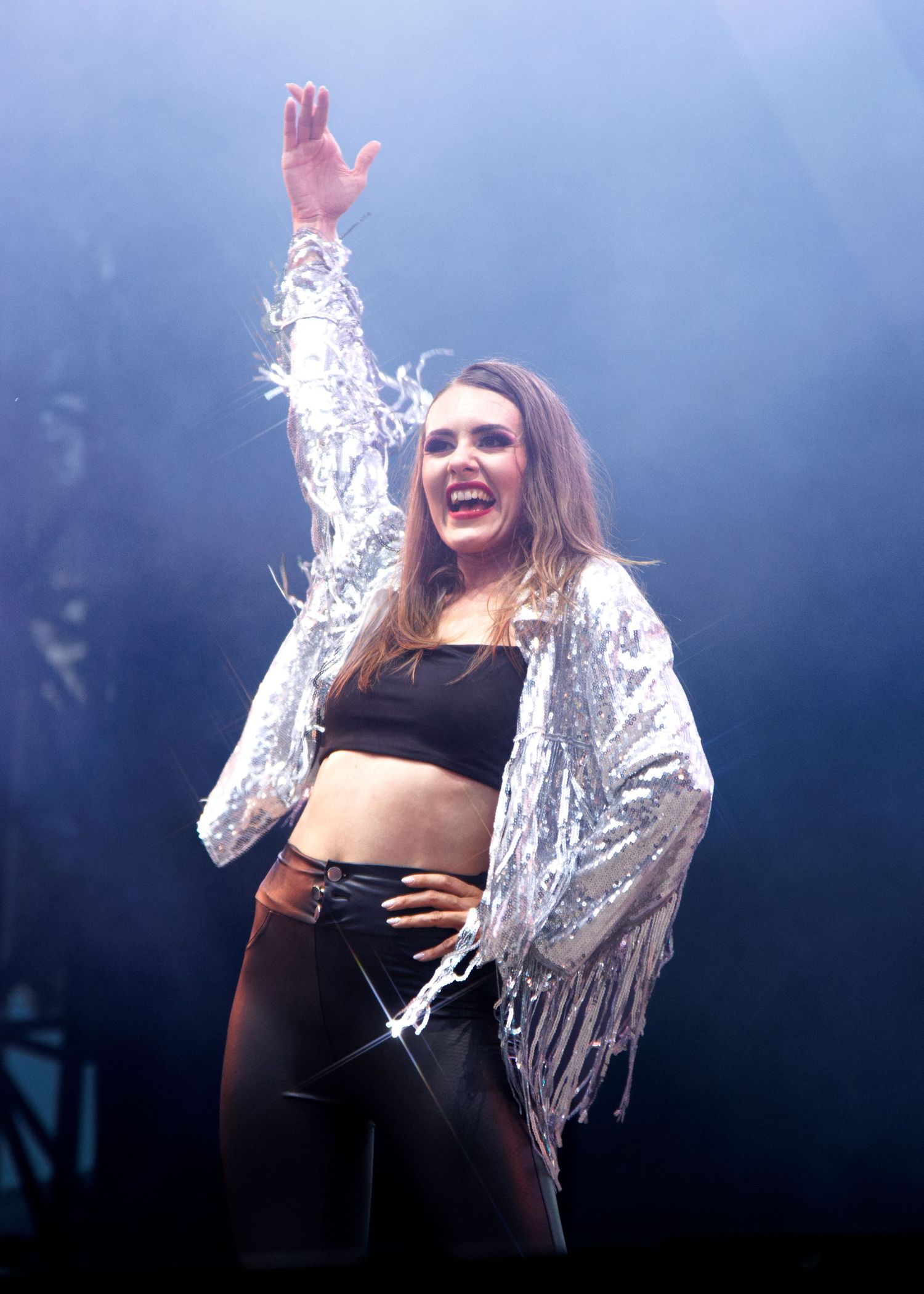A sequence of performance shots shows someone in a black outfit and shimmery silver jacket making expressive gestures on stage.