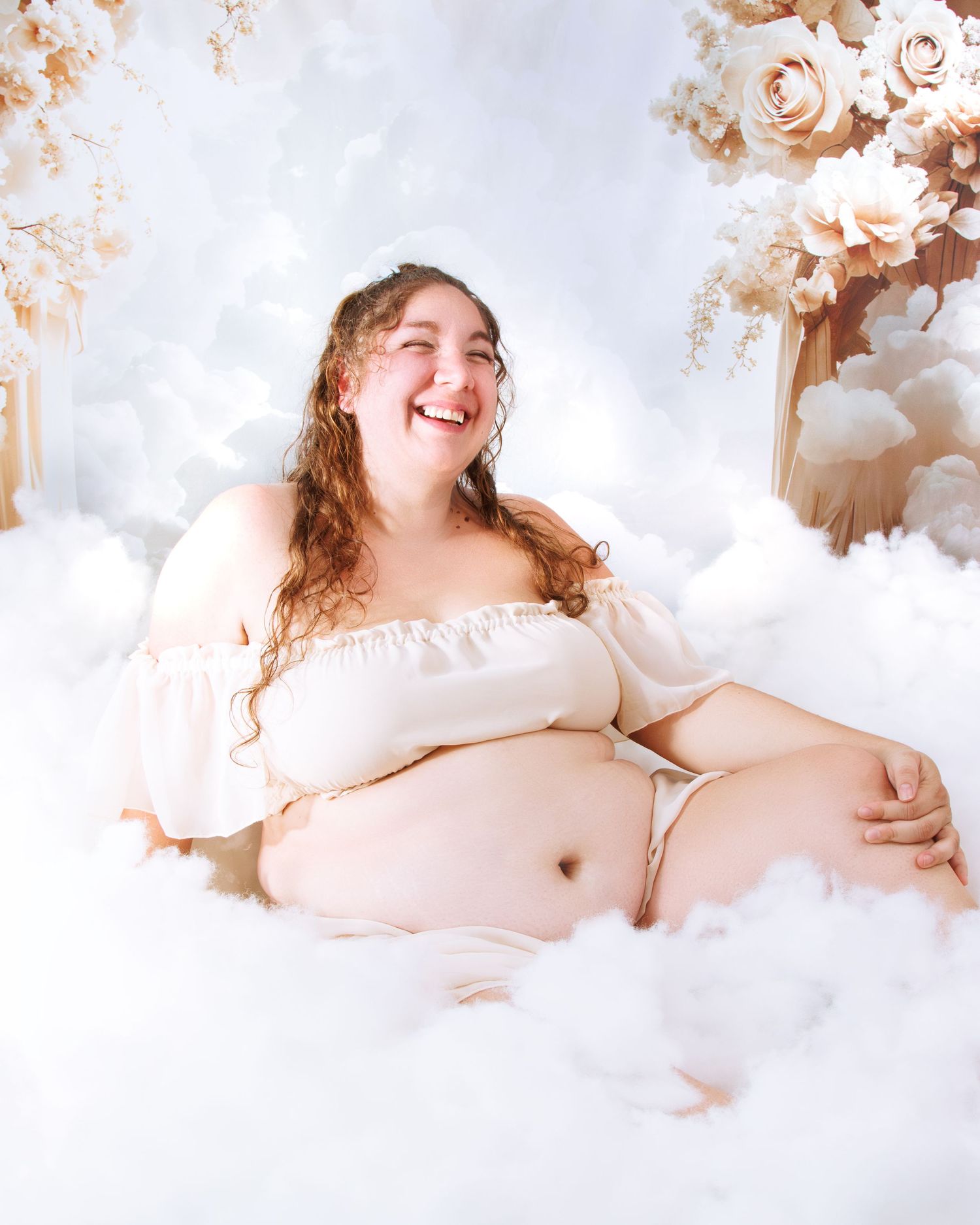 Joyful maternity portrait with soft lighting and floral decorations.