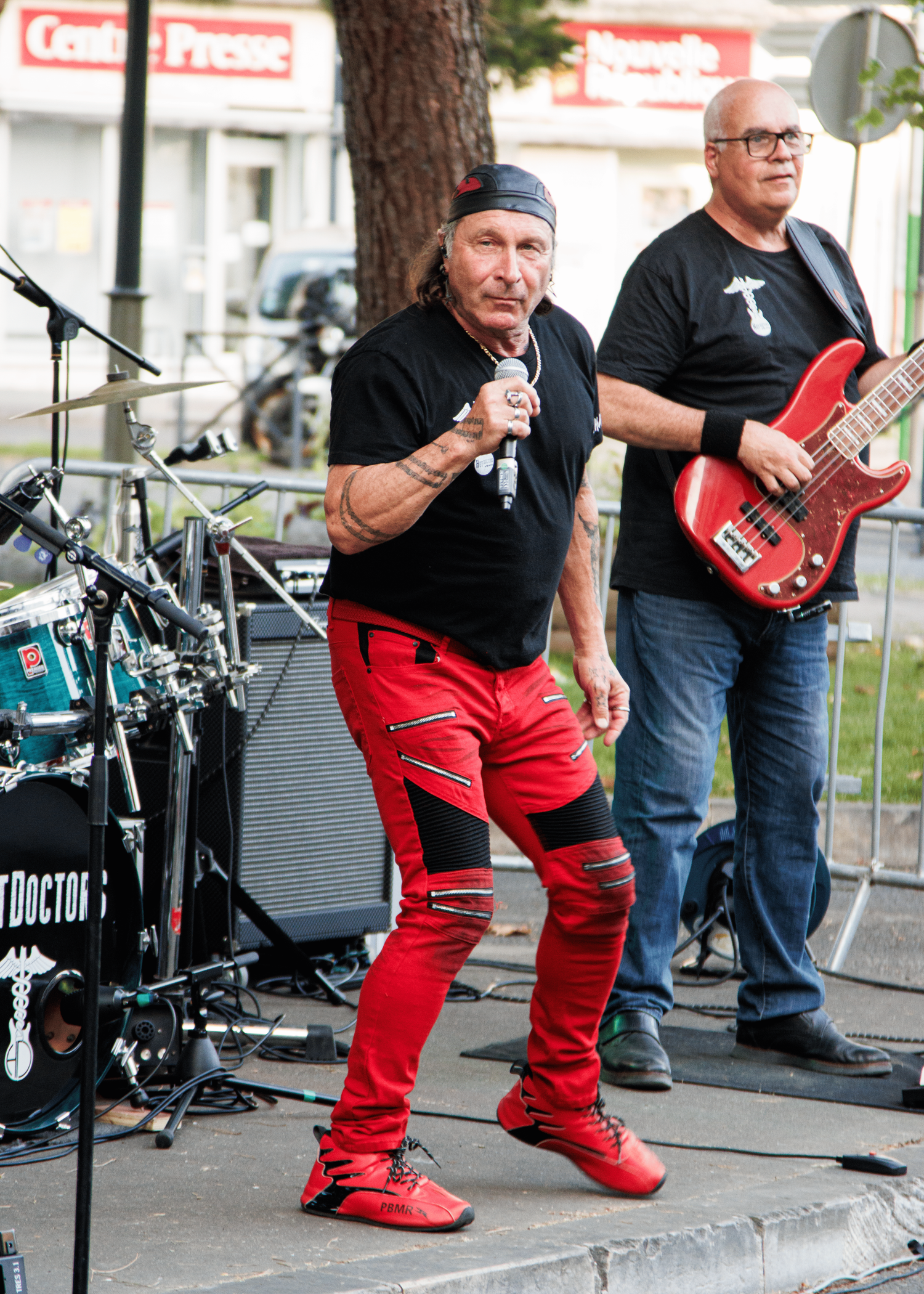 Band members performing on outdoor stage with musical equipment and instruments.