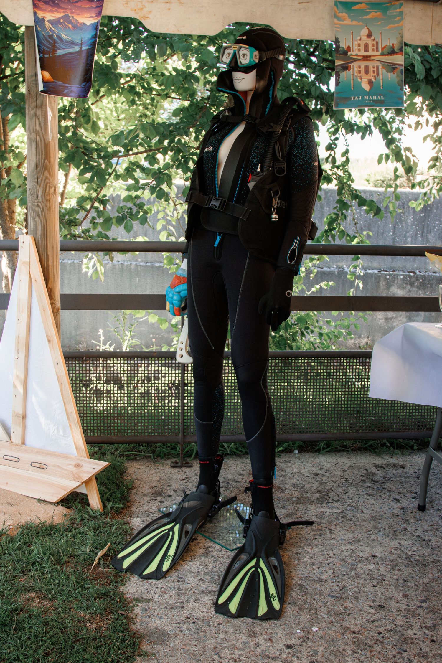 Full scuba diving suit displayed on mannequin with flippers and gear at outdoor wedding decor.
