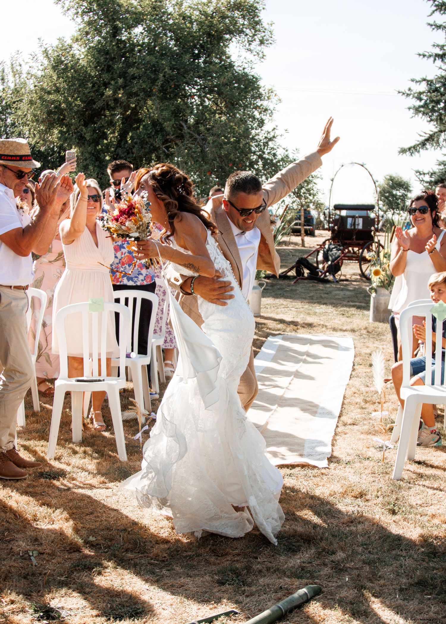 Wedding guests create a joyous dance tunnel as a bride dances through in her white gown at an outdoor celebration.