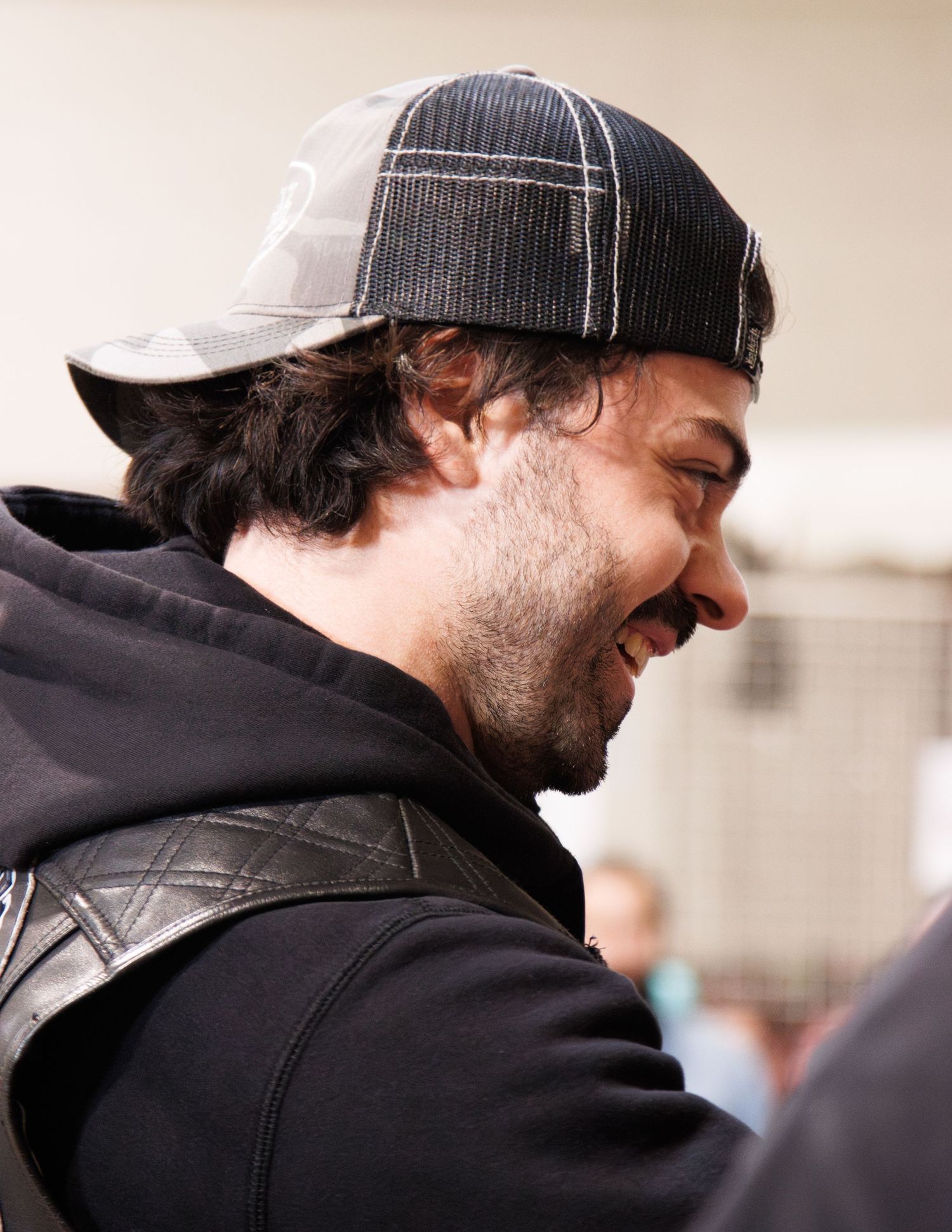 Side profile of someone laughing while wearing a striped baseball cap.
