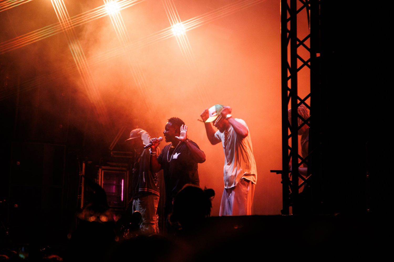 Silhouettes of performers on a dimly lit stage with red and orange lighting effects creating a dramatic atmosphere.