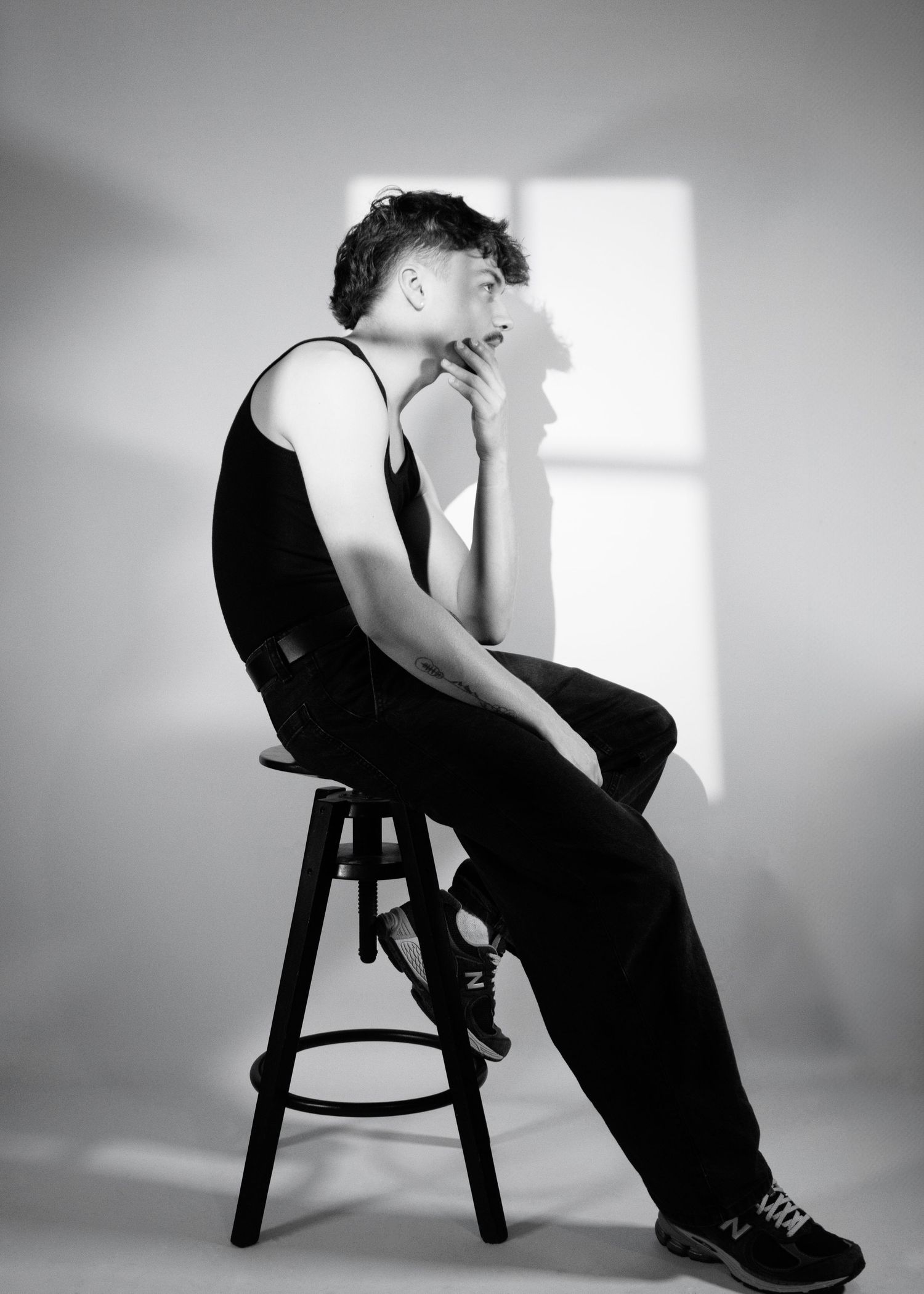 Black and white artistic portrait series showing a figure seated on a stool in various contemplative poses.