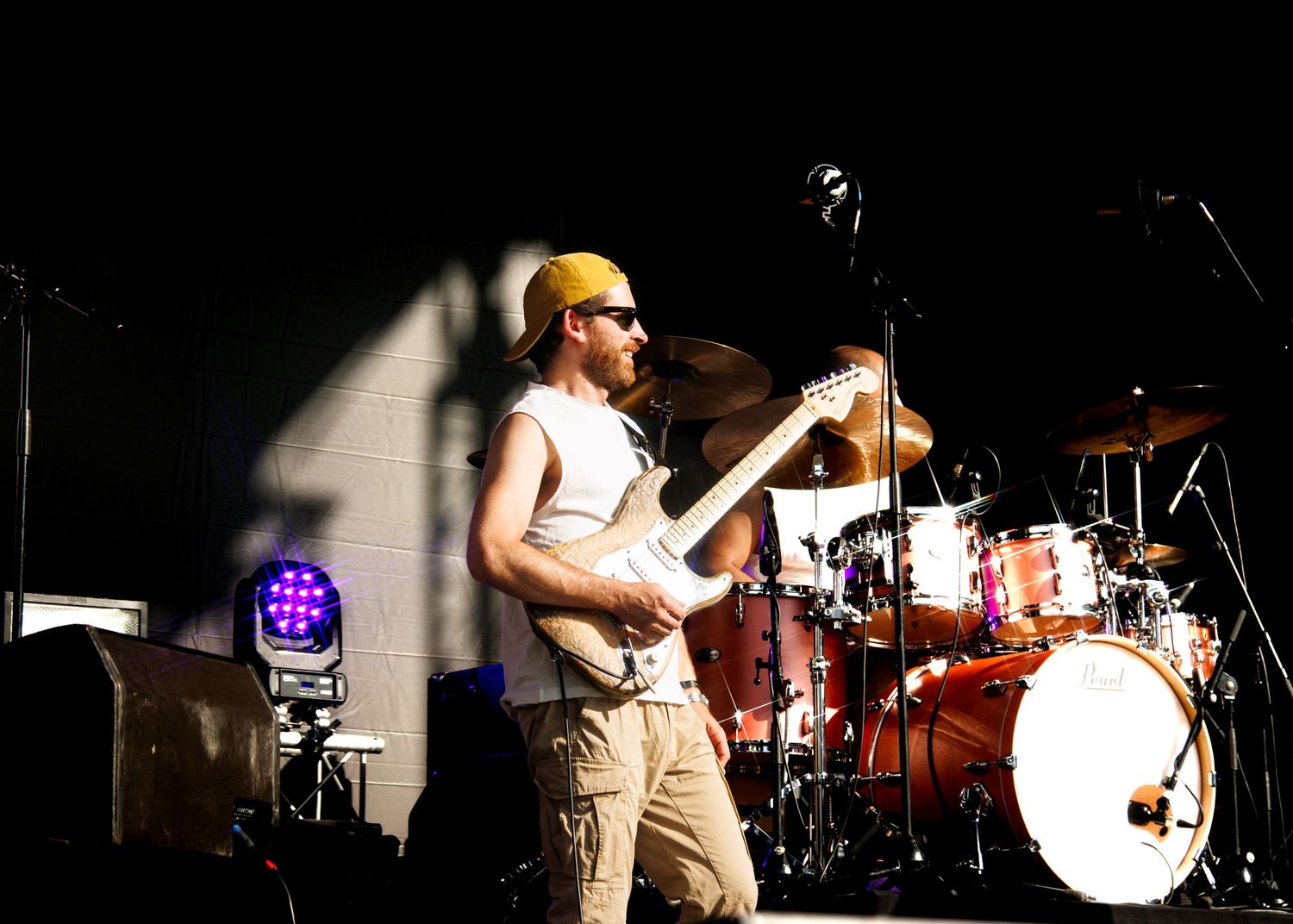 Band members performing on stage with dramatic backlighting and silhouettes against dark background.