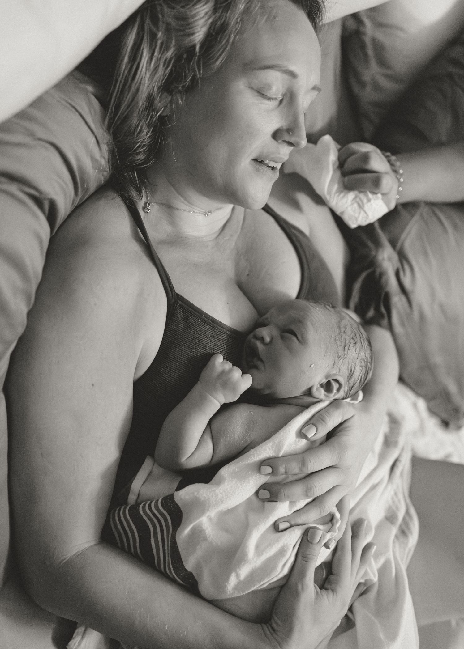 A tender black and white photo series showing intimate moments of skin-to-skin contact between parent and newborn.