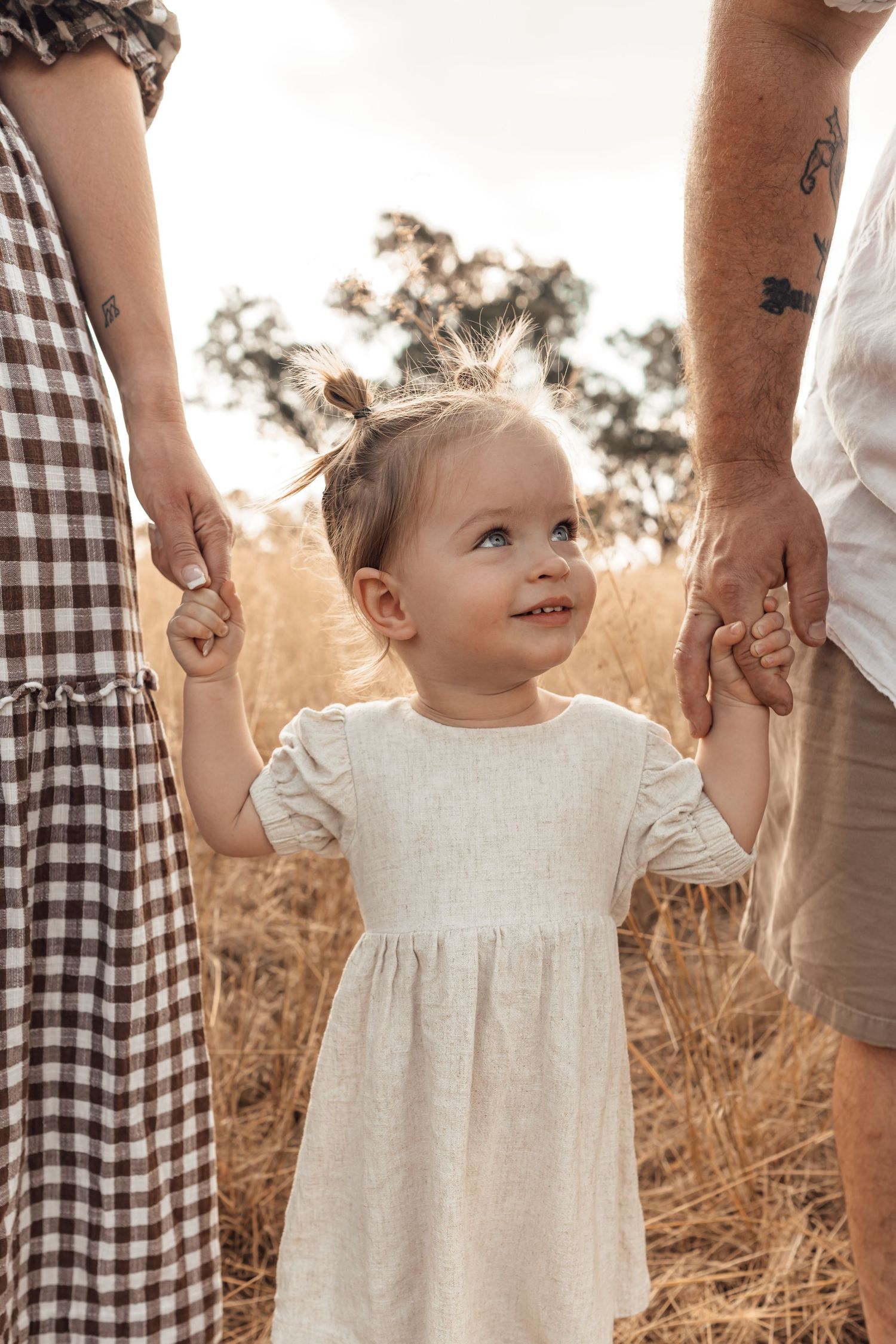 Perth Family Photographer, cute little toddler with mum and dad in golden field holding hands