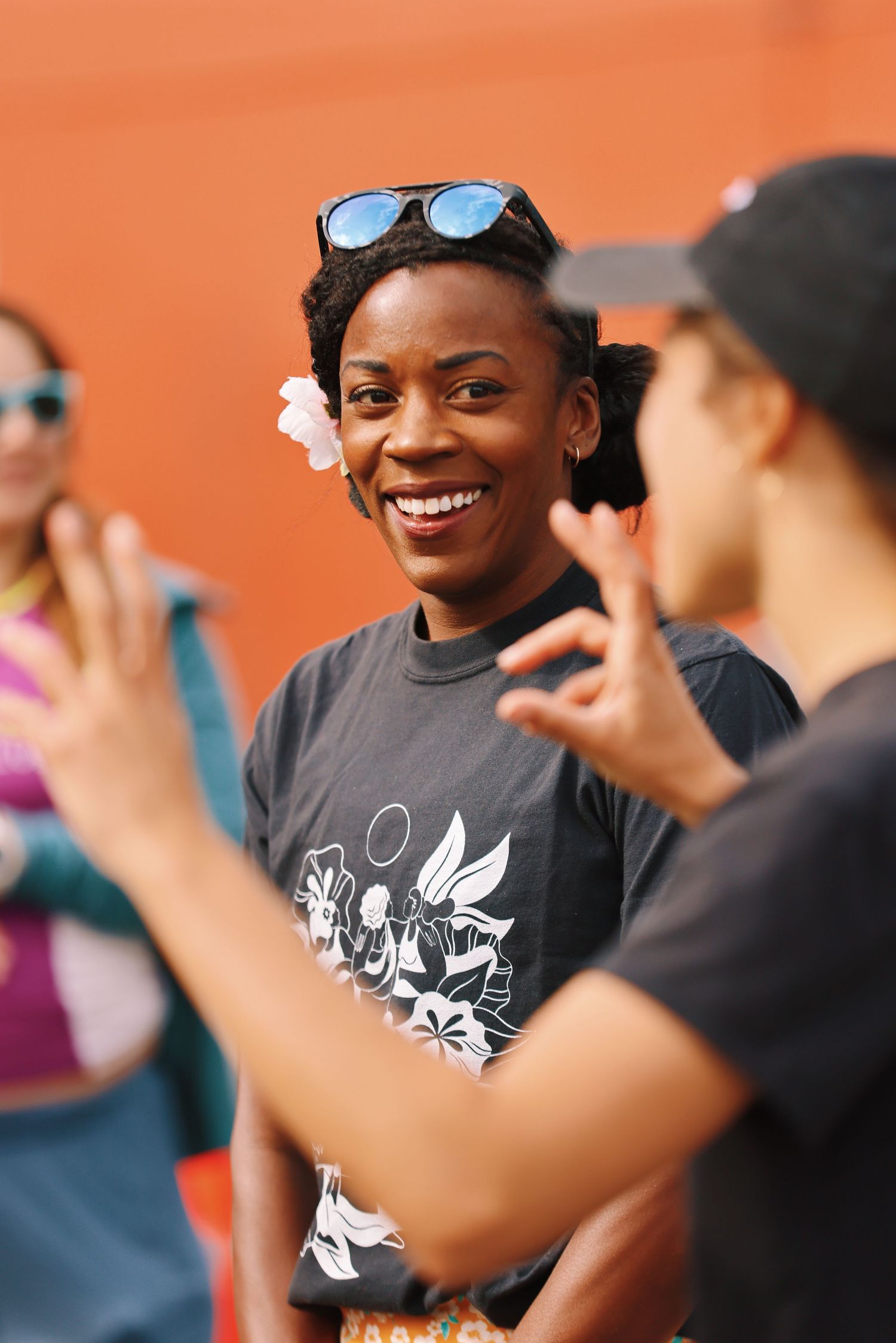 Candid shot of someone in a graphic t-shirt with sunglasses atop their head during outdoor gathering.
