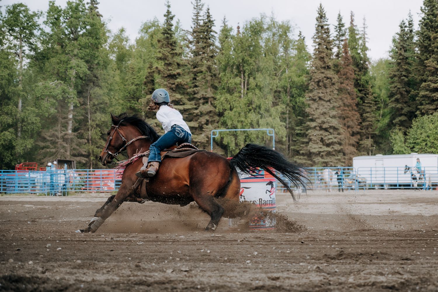 Horse and rider galloping through a dirt arena during a rodeo event.