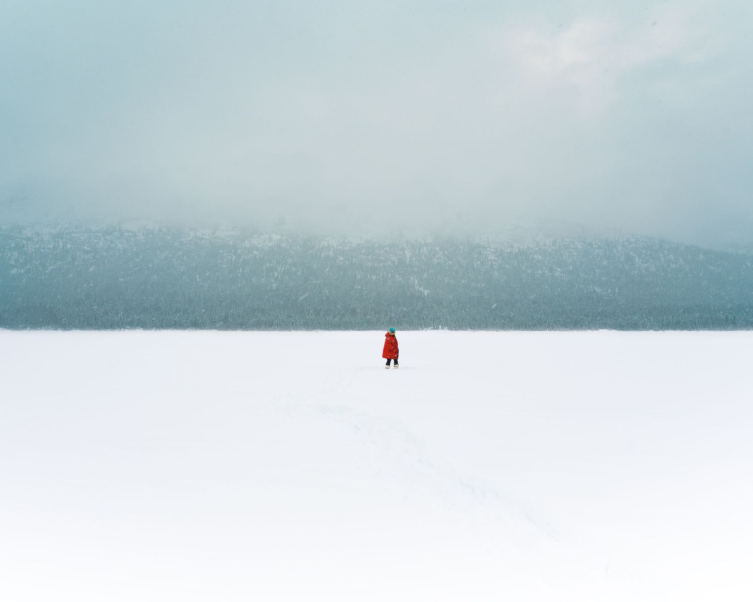 A serene winter landscape with snow-covered mountains and misty skies.